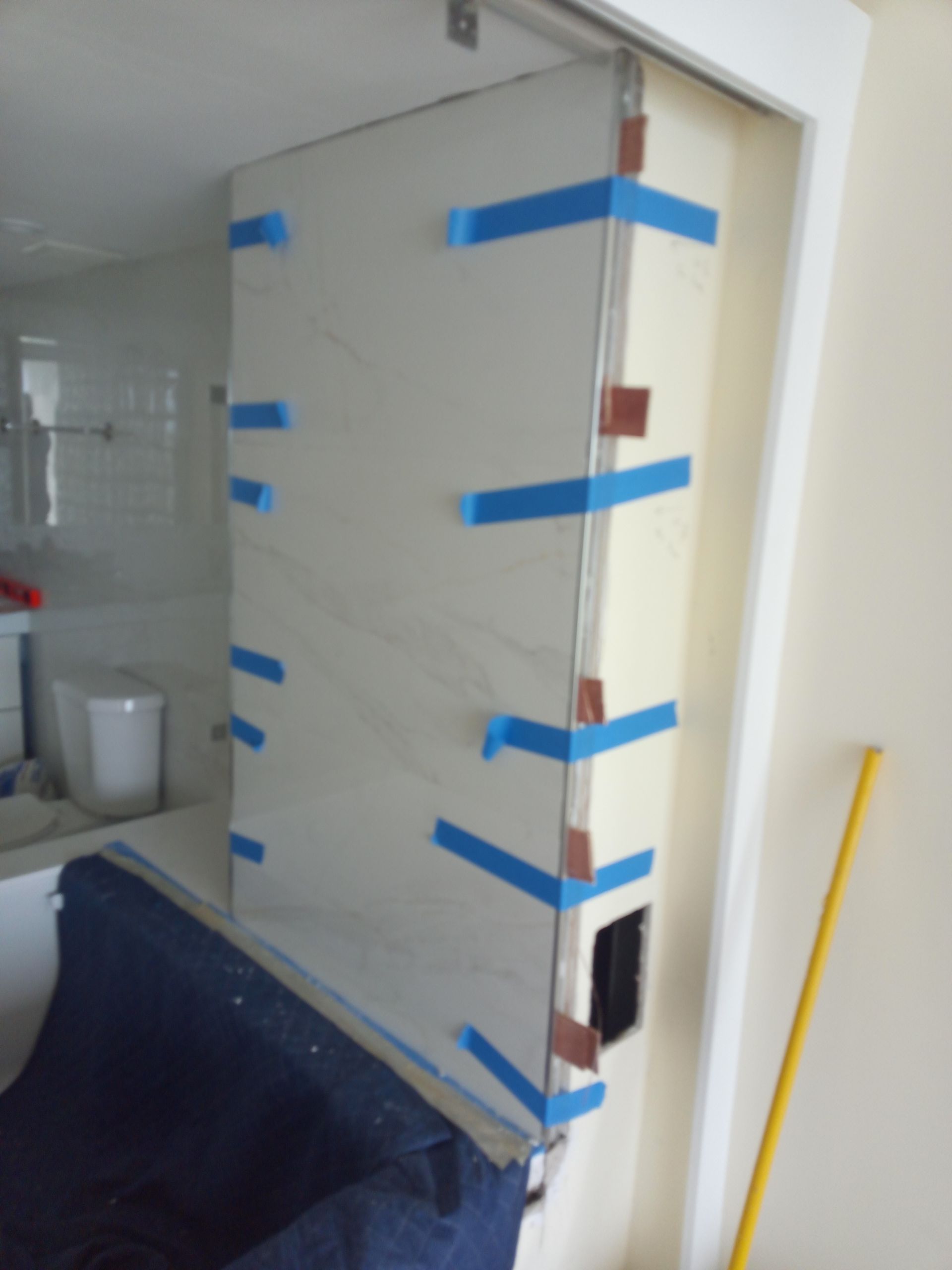 A door is taped to a wall in a bathroom