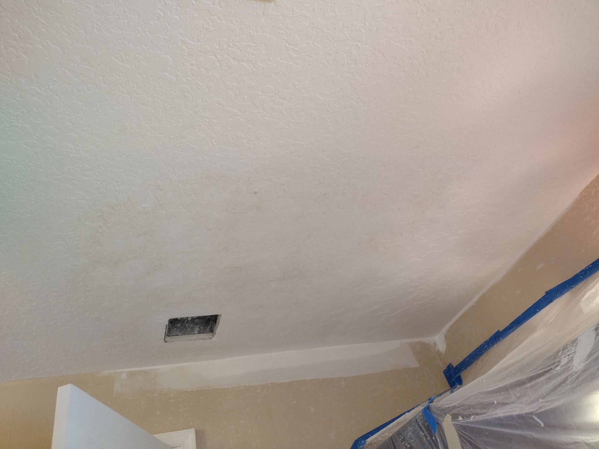 A room with a ceiling that is being painted white