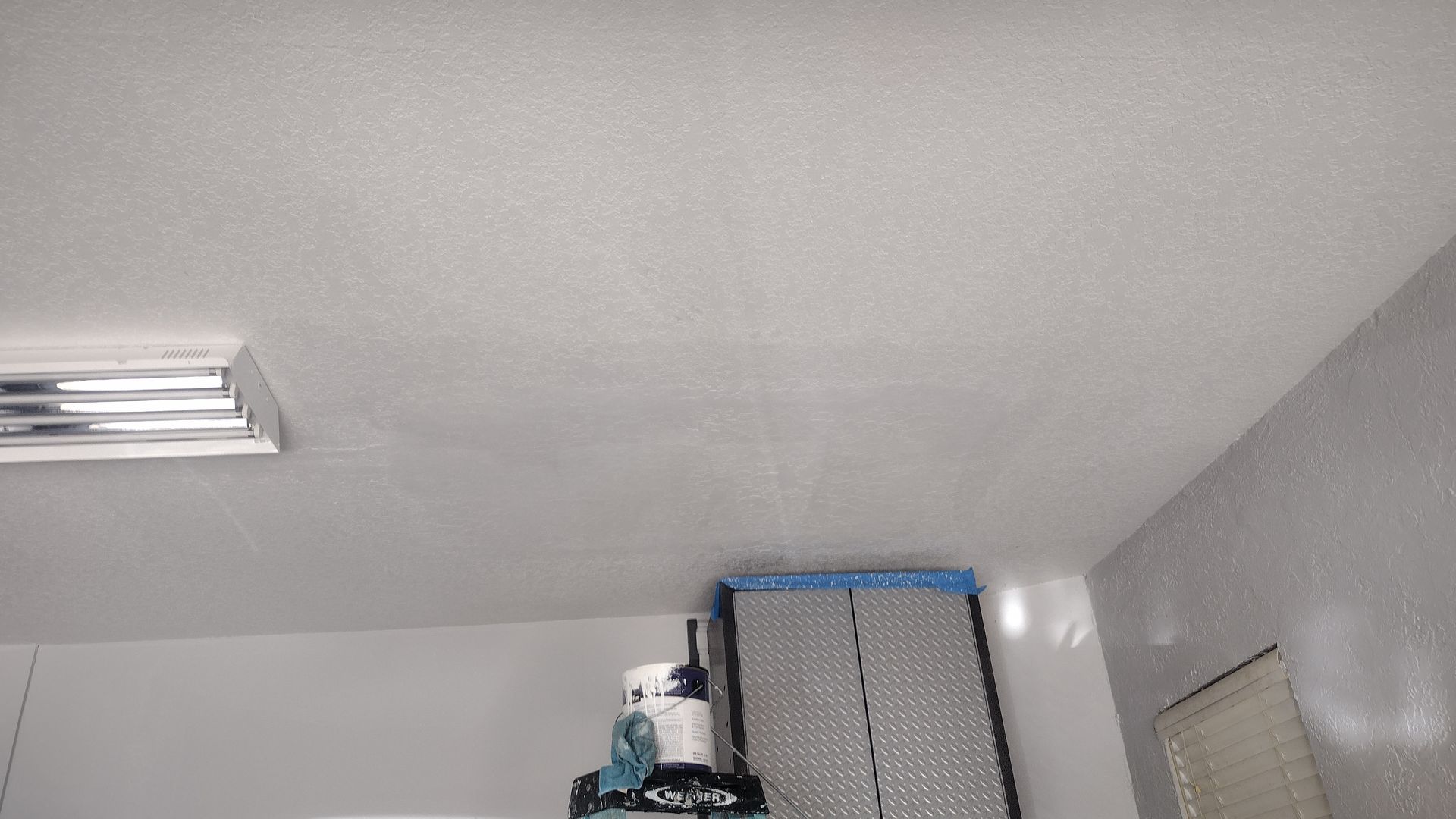 A ceiling with a light on it and a shelf with a box on it.