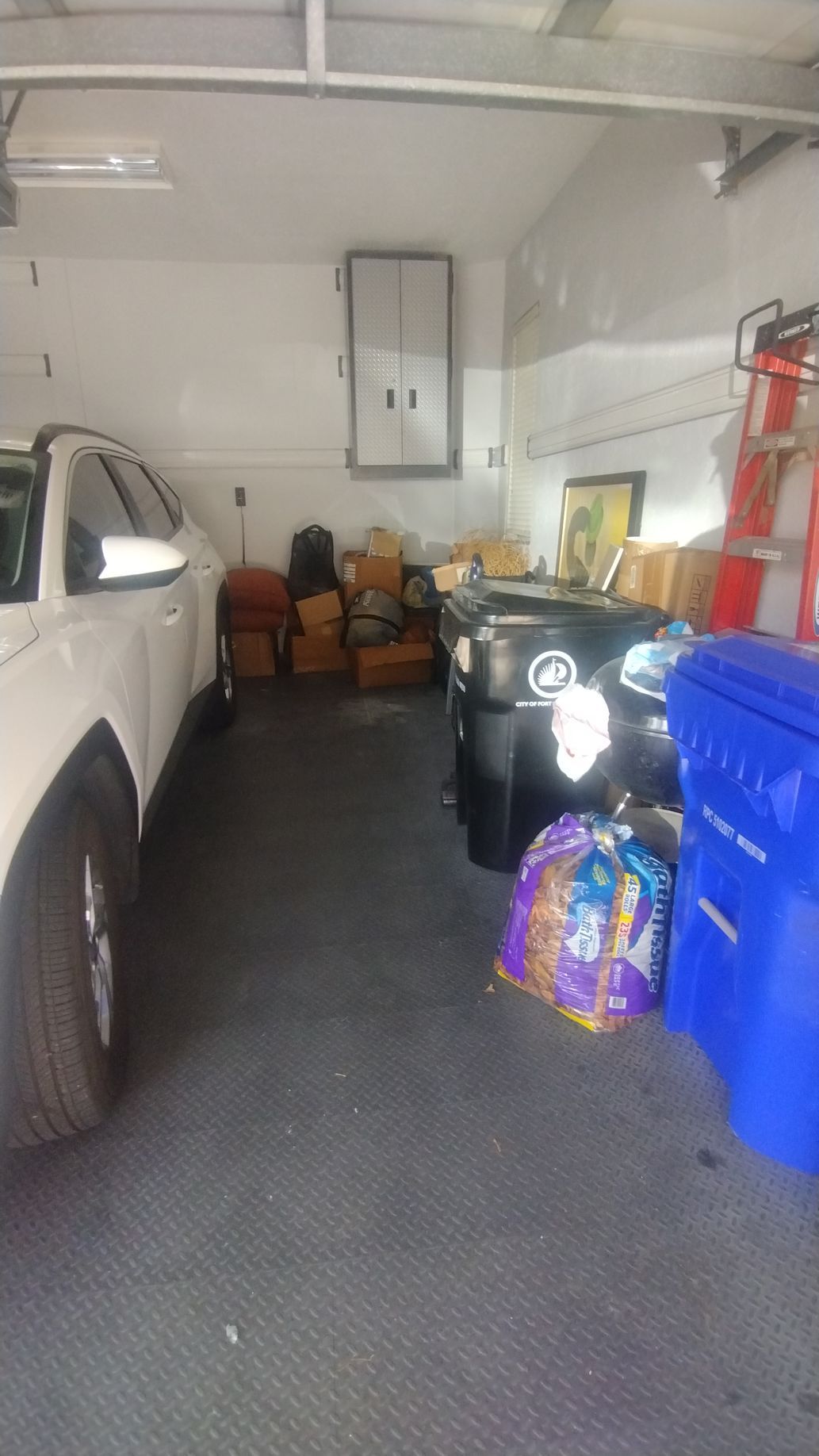 A white suv is parked in a garage filled with lots of junk.