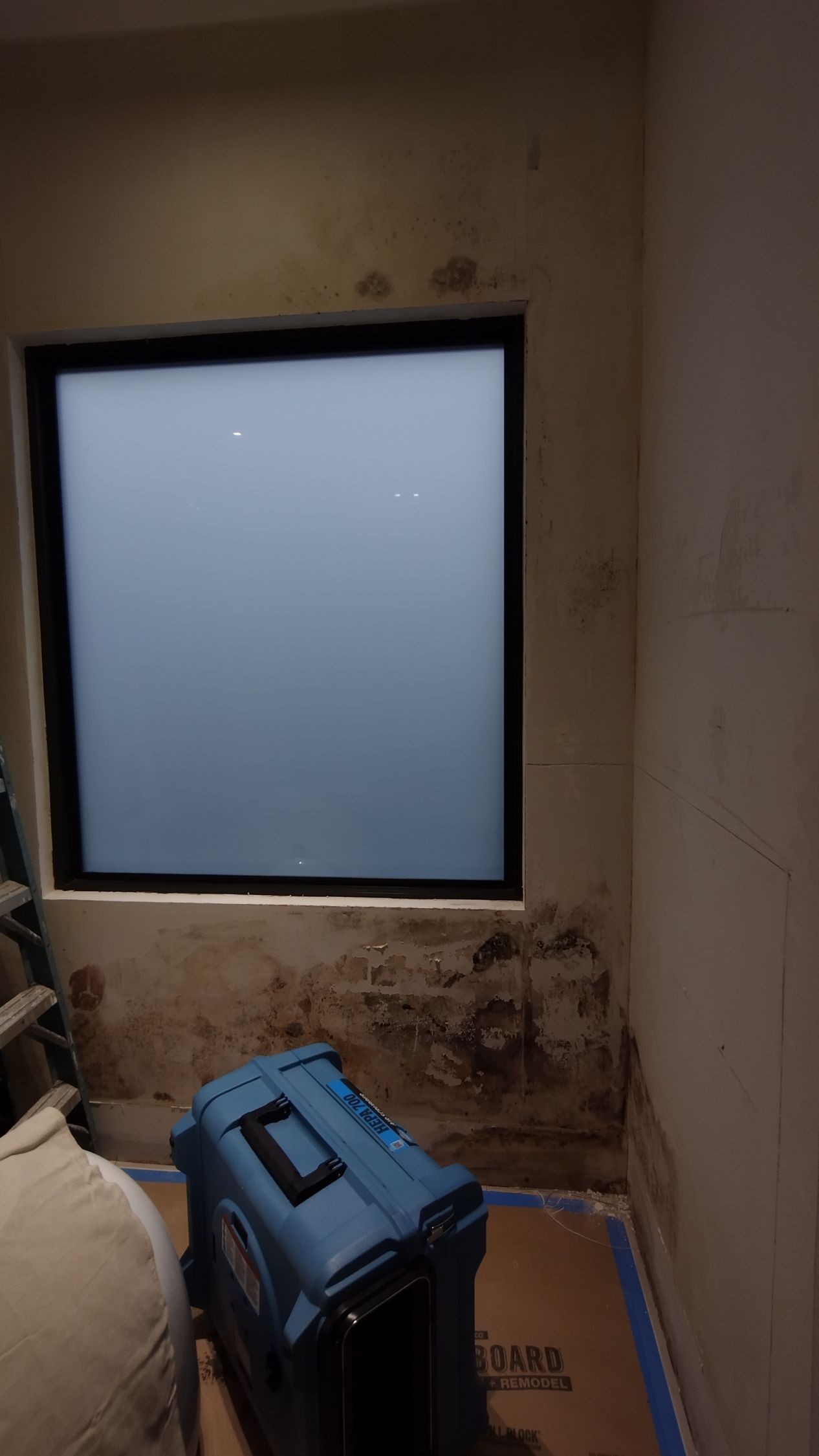 A room with a window and a blue box on the floor.
