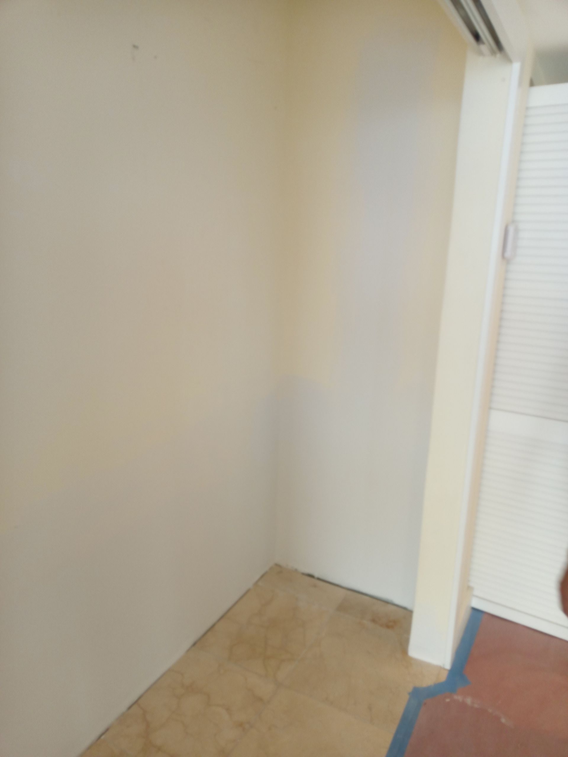 An empty room with a tiled floor and a white wall.