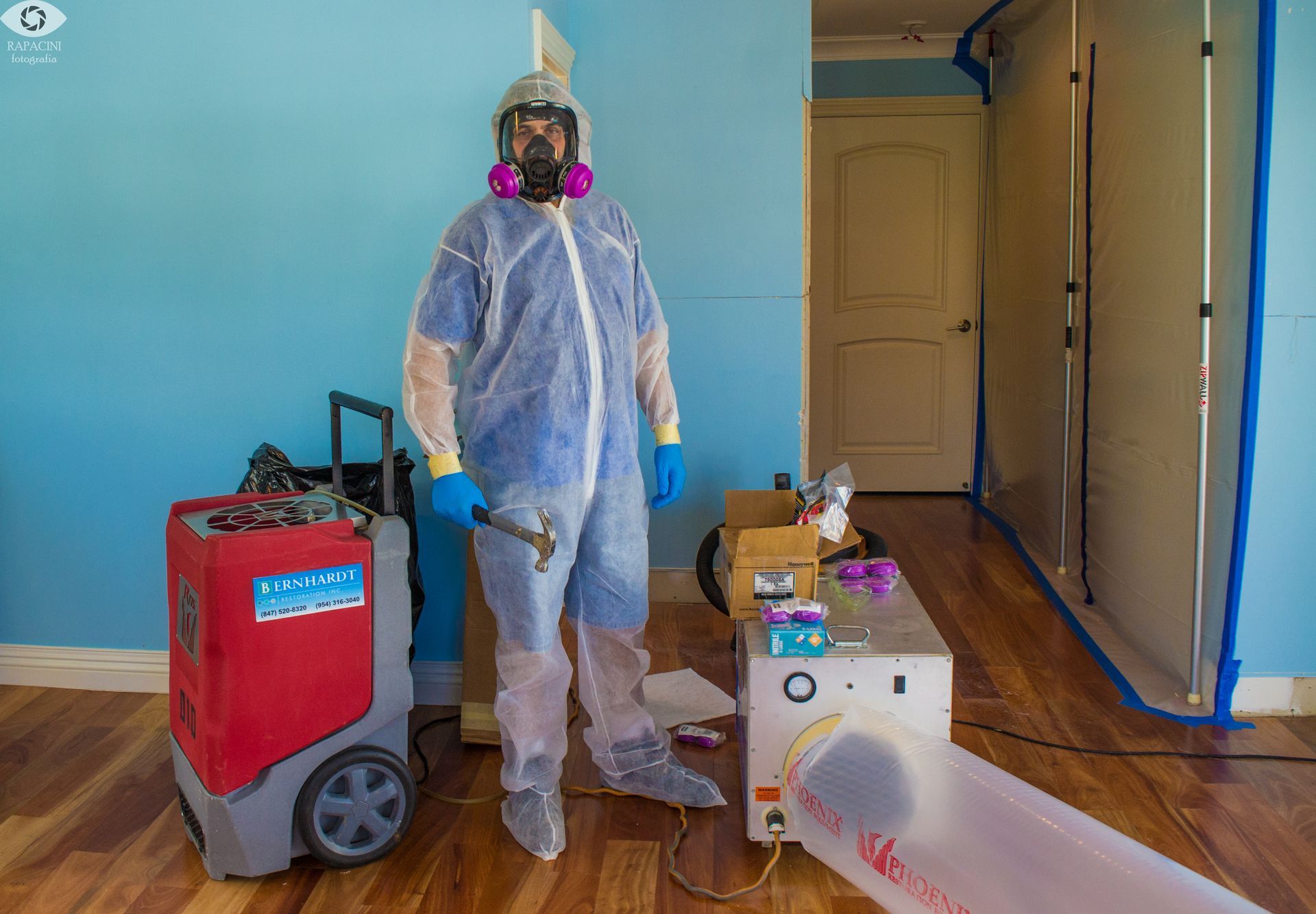 A man in a protective suit is standing in a room next to a machine.