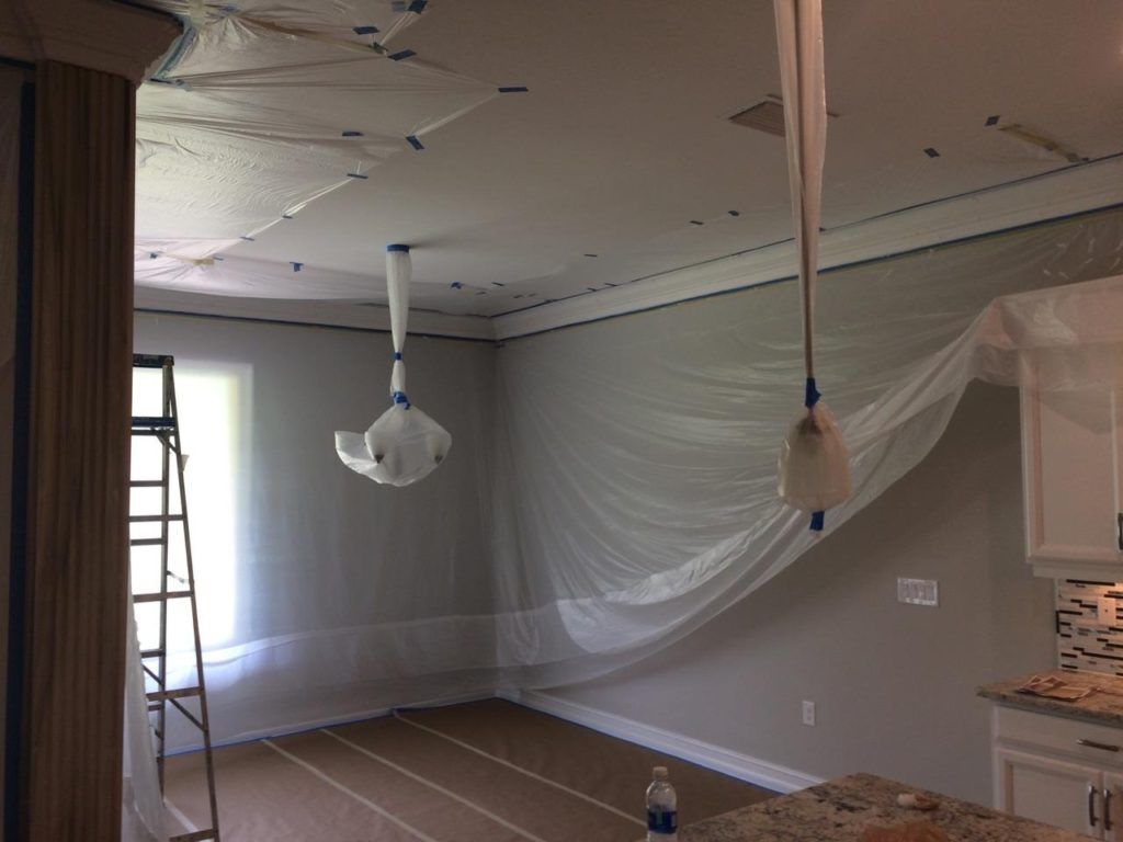 A room with a ceiling fan hanging from it and a ladder.