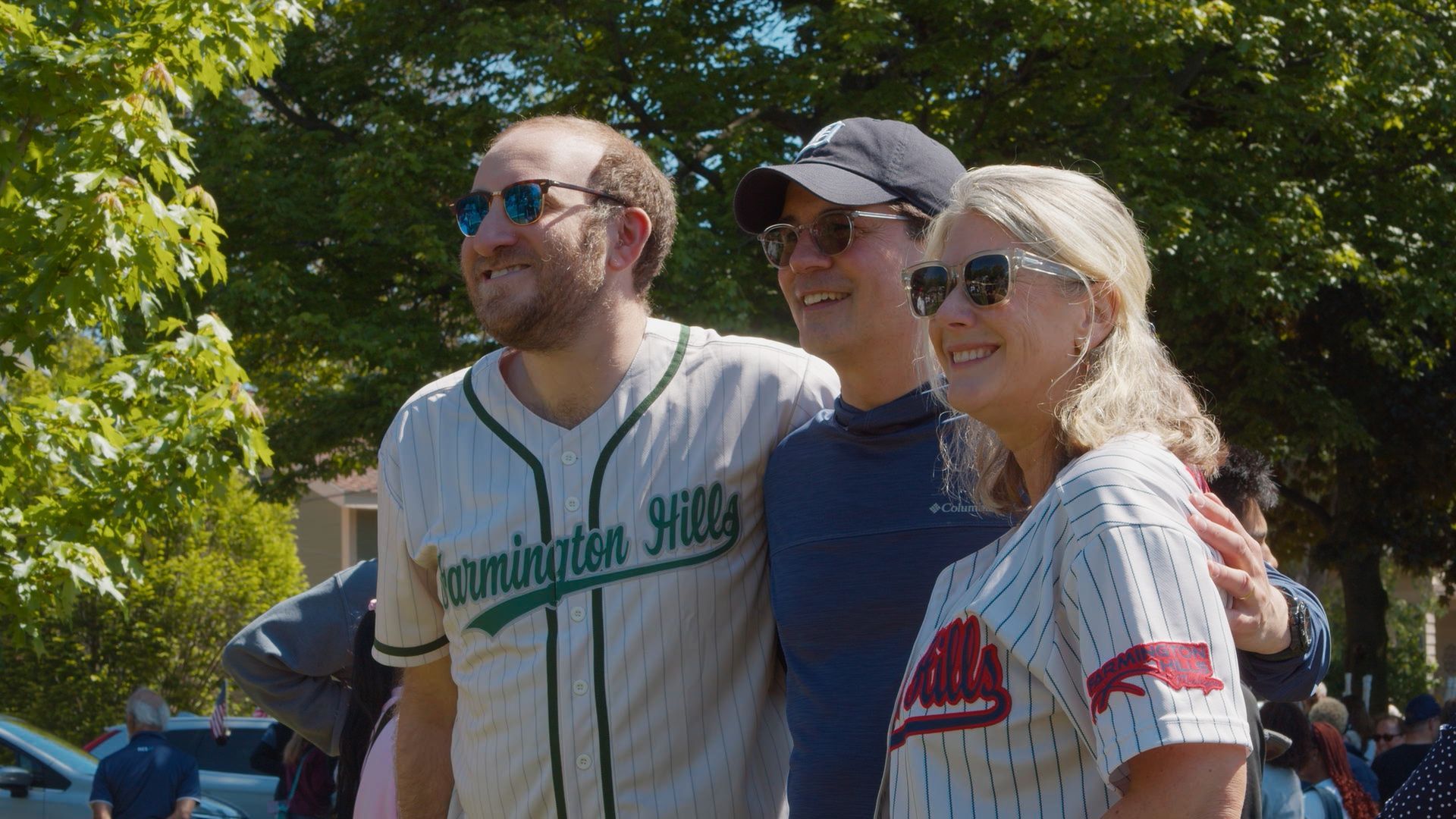 Michael Sawicky in the memorial day parade in Farmington Hills. Three smiling fans in baseball jerseys posing outdoors in sunlight