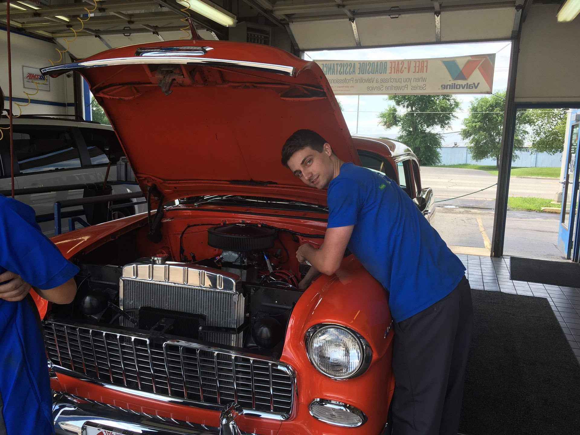 Woman mechanic in overalls checking car fluids in an auto repair shop.