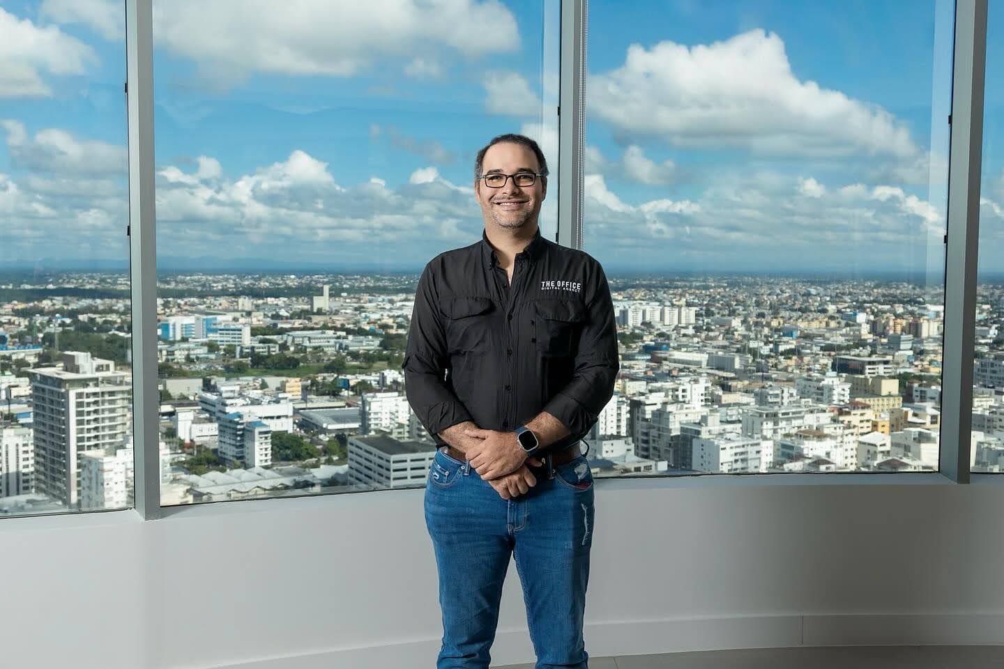 A man is standing in front of a large window overlooking a city.