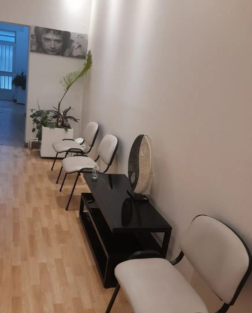 Una sala de espera con sillas, una mesa y un ventilador.