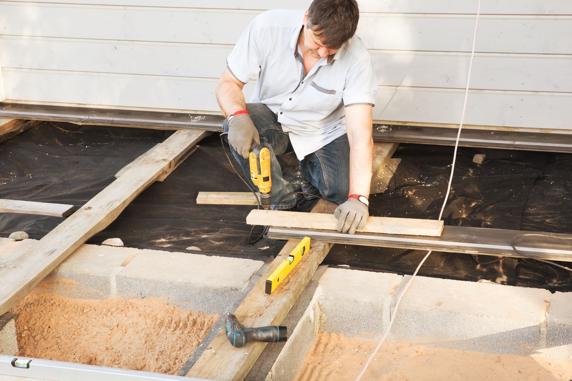 Carpenter installing decking boards on a residential home deck. Carpenter installing decking boards on a residential home deck.
