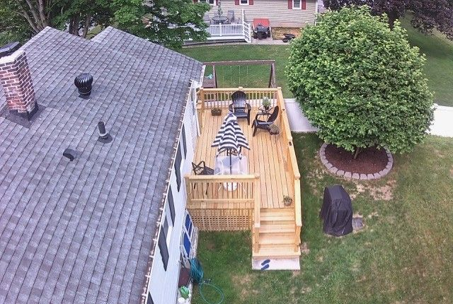Aerial view of wooden deck with furniture and grill next to house.