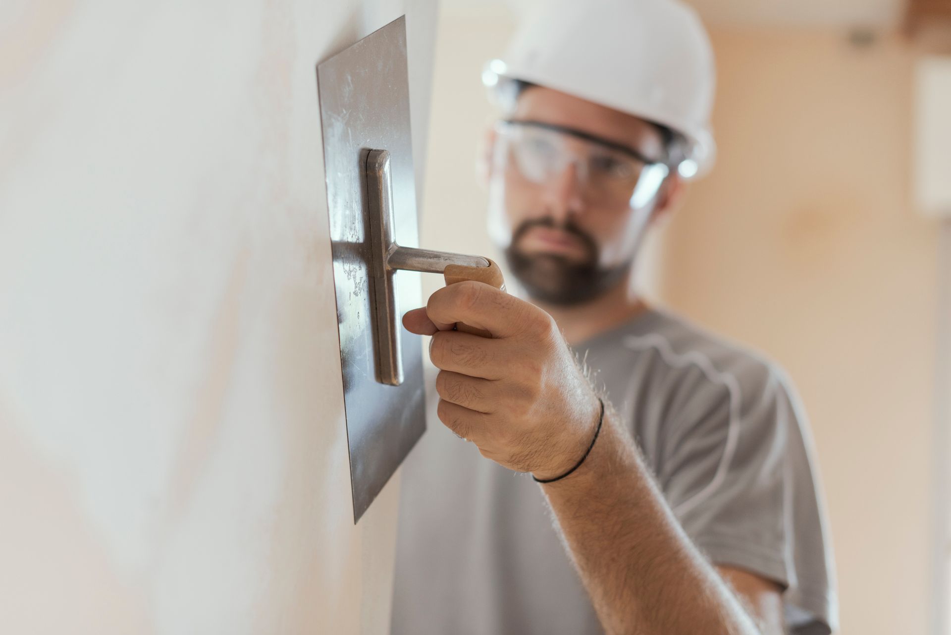 Professional contractor applying plaster to interior wall with trowel during home renovation