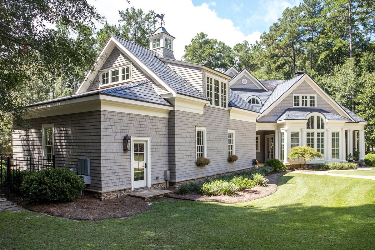Modern gray house with multiple gables and a landscaped lawn.