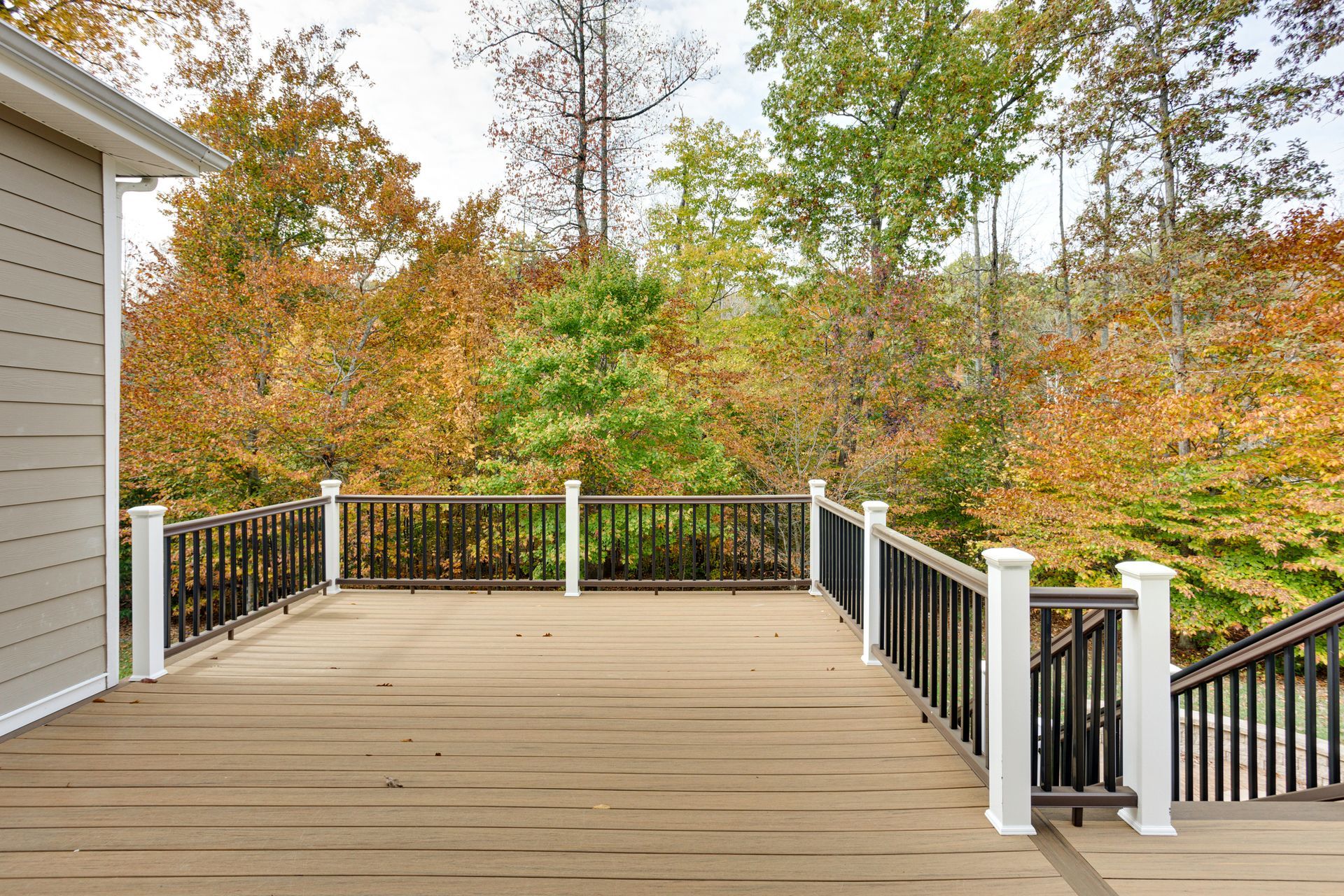 Wooden deck with railing overlooking autumn trees.
