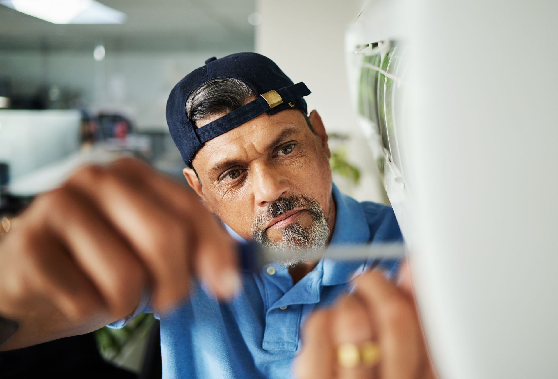An air conditioning contractor using a screwdriver to perform a unit's maintenance.