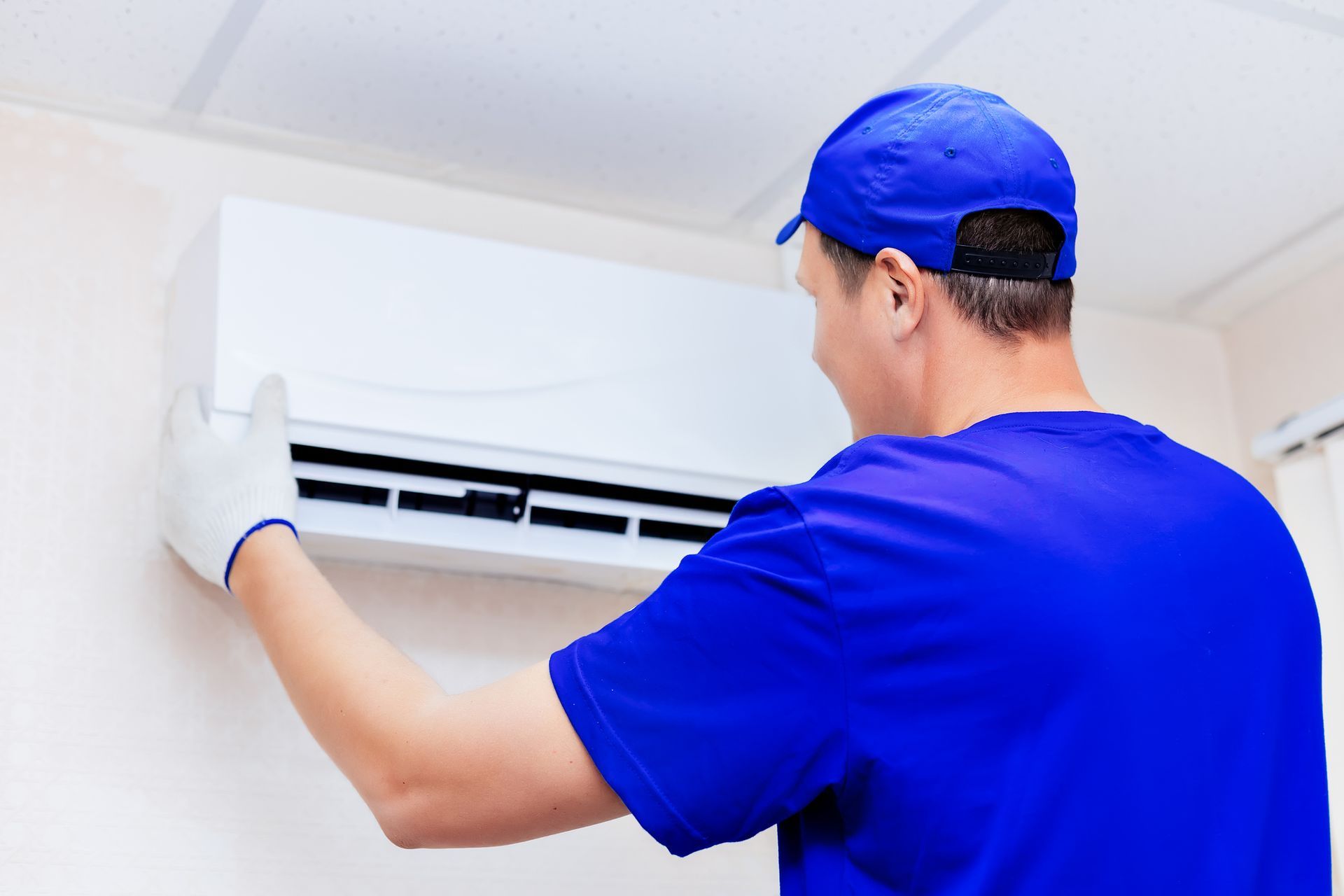 A male Air Conditioner Installation Contractor installing an AC.