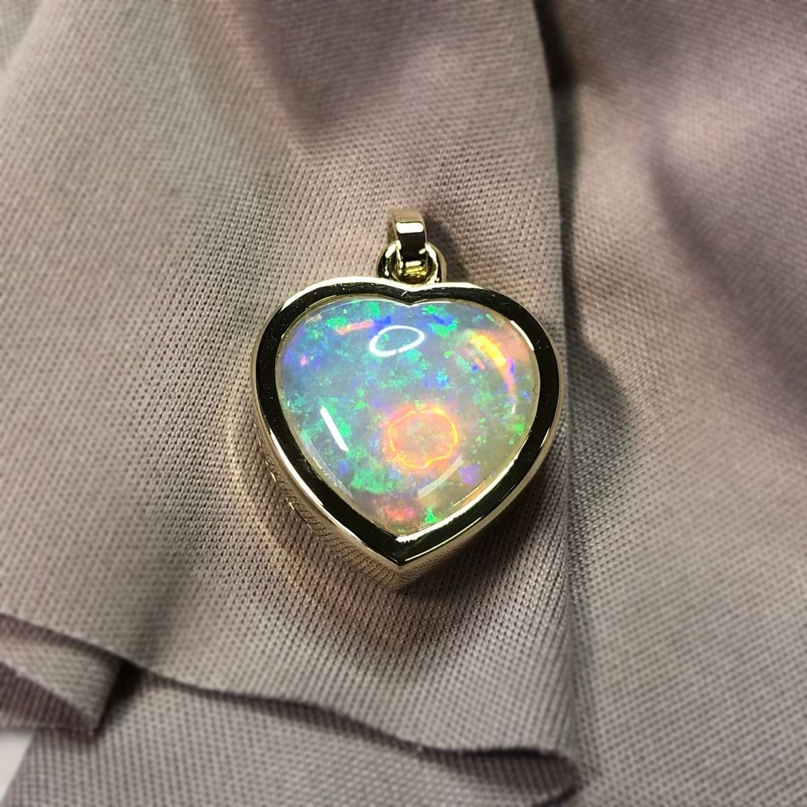 Ein herzförmiger Anhänger sitzt auf einem grauen Tuch