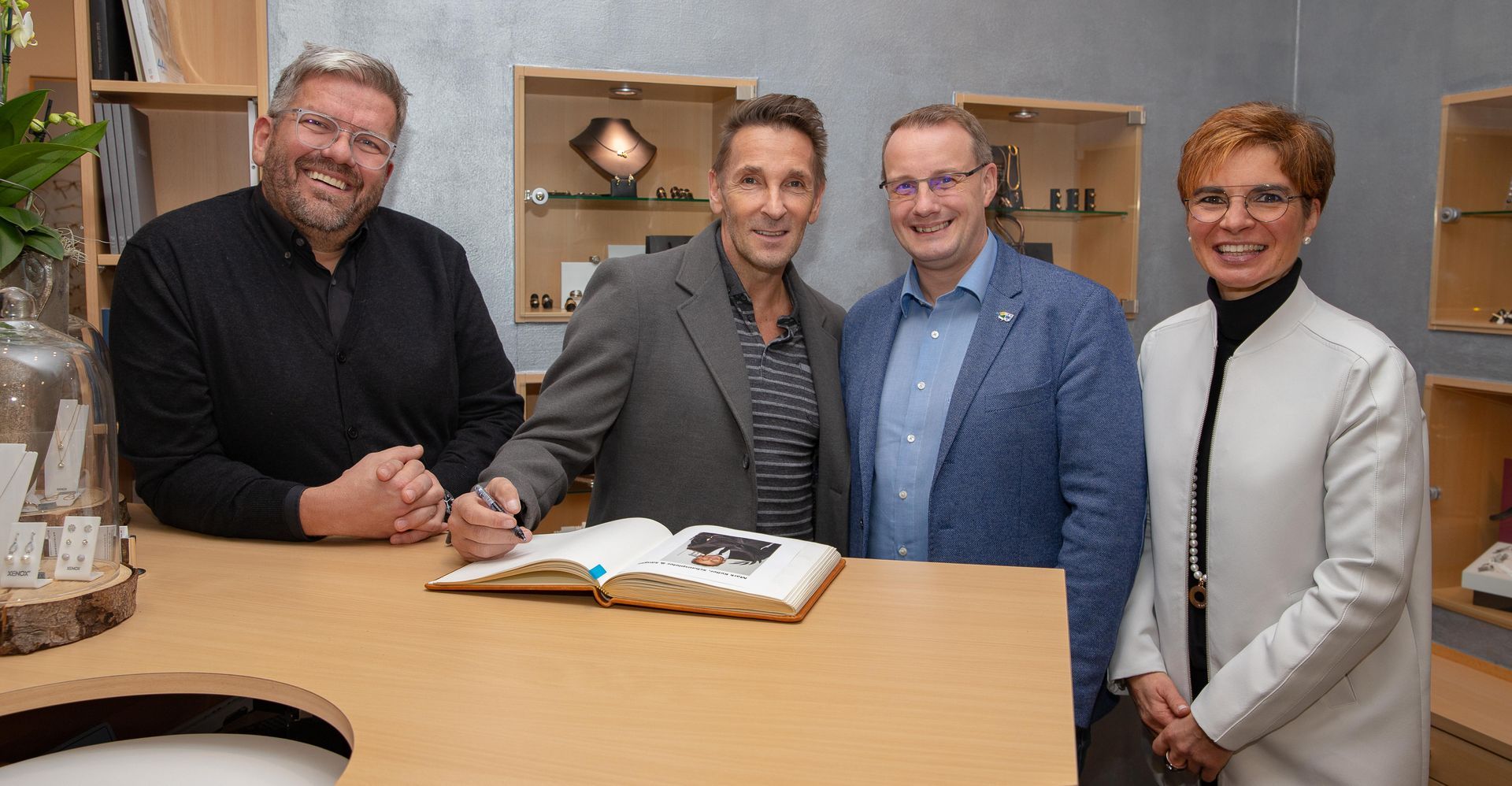 Eine Gruppe von Menschen steht um einen Tisch herum, auf dem ein Buch liegt