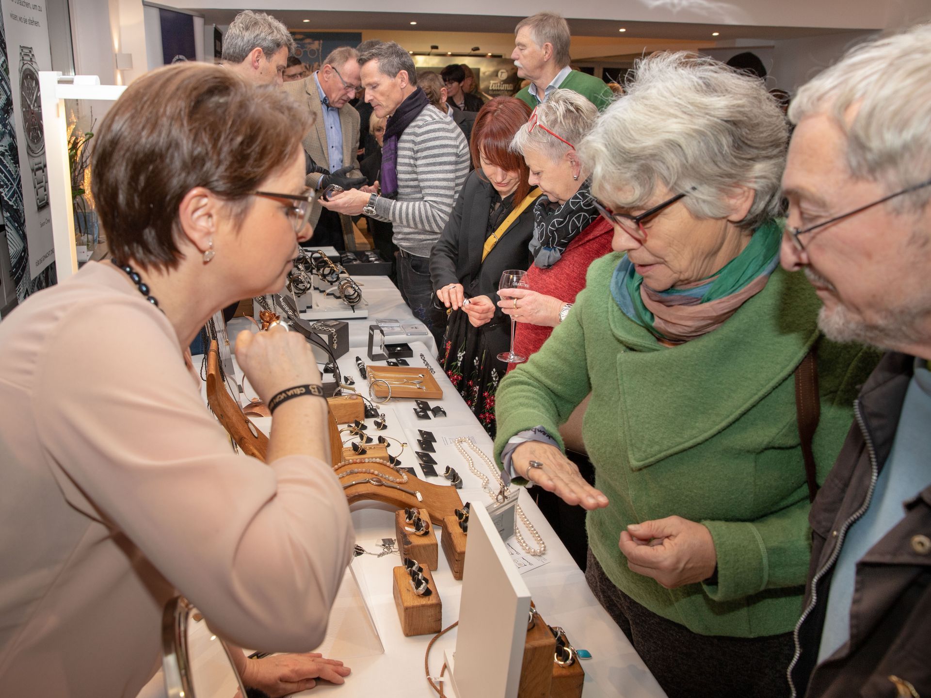 Eine Gruppe von Menschen betrachtet einen Tisch voller Schmuck
