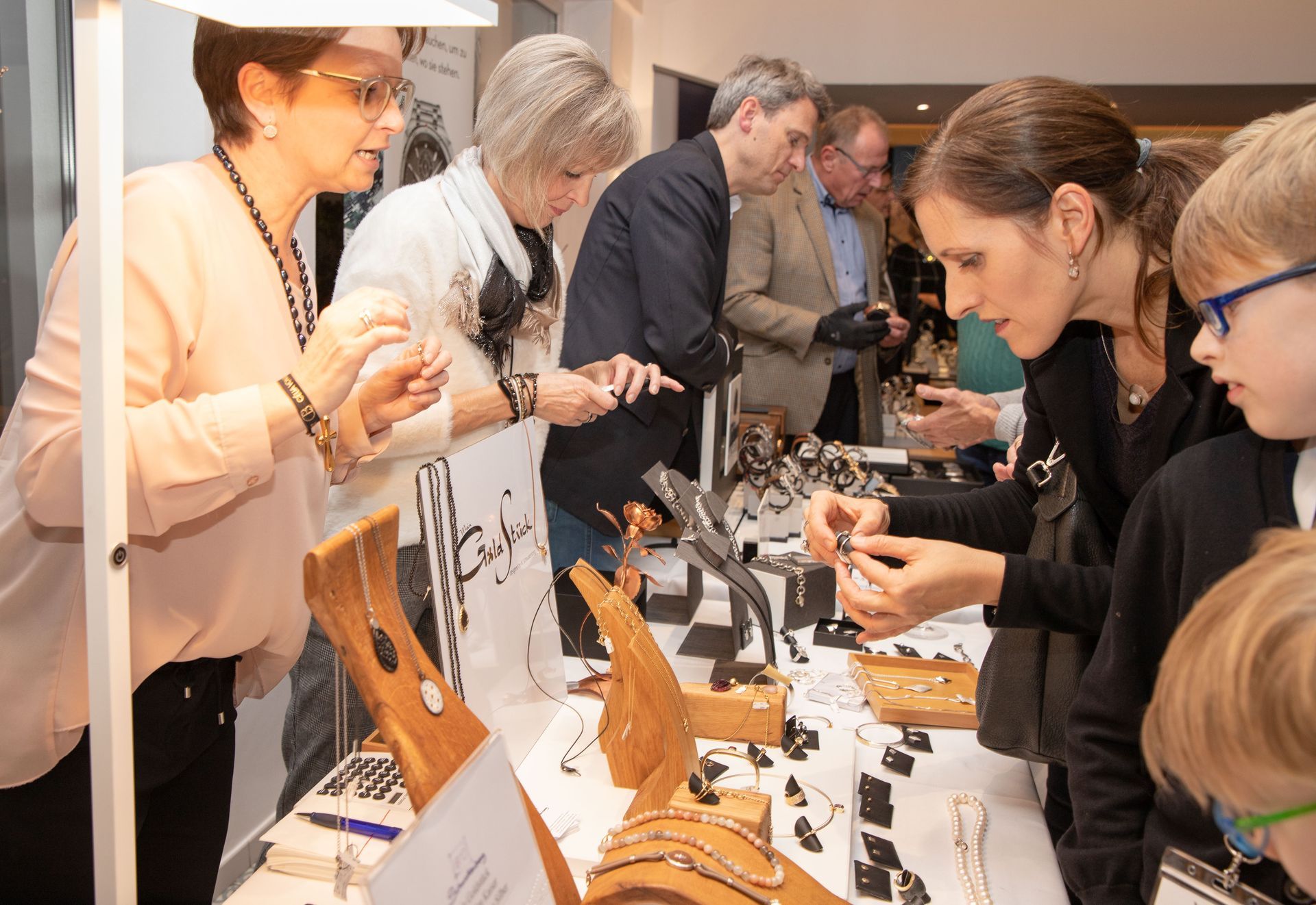 Eine Gruppe von Menschen schaut sich an einem Tisch Schmuck an