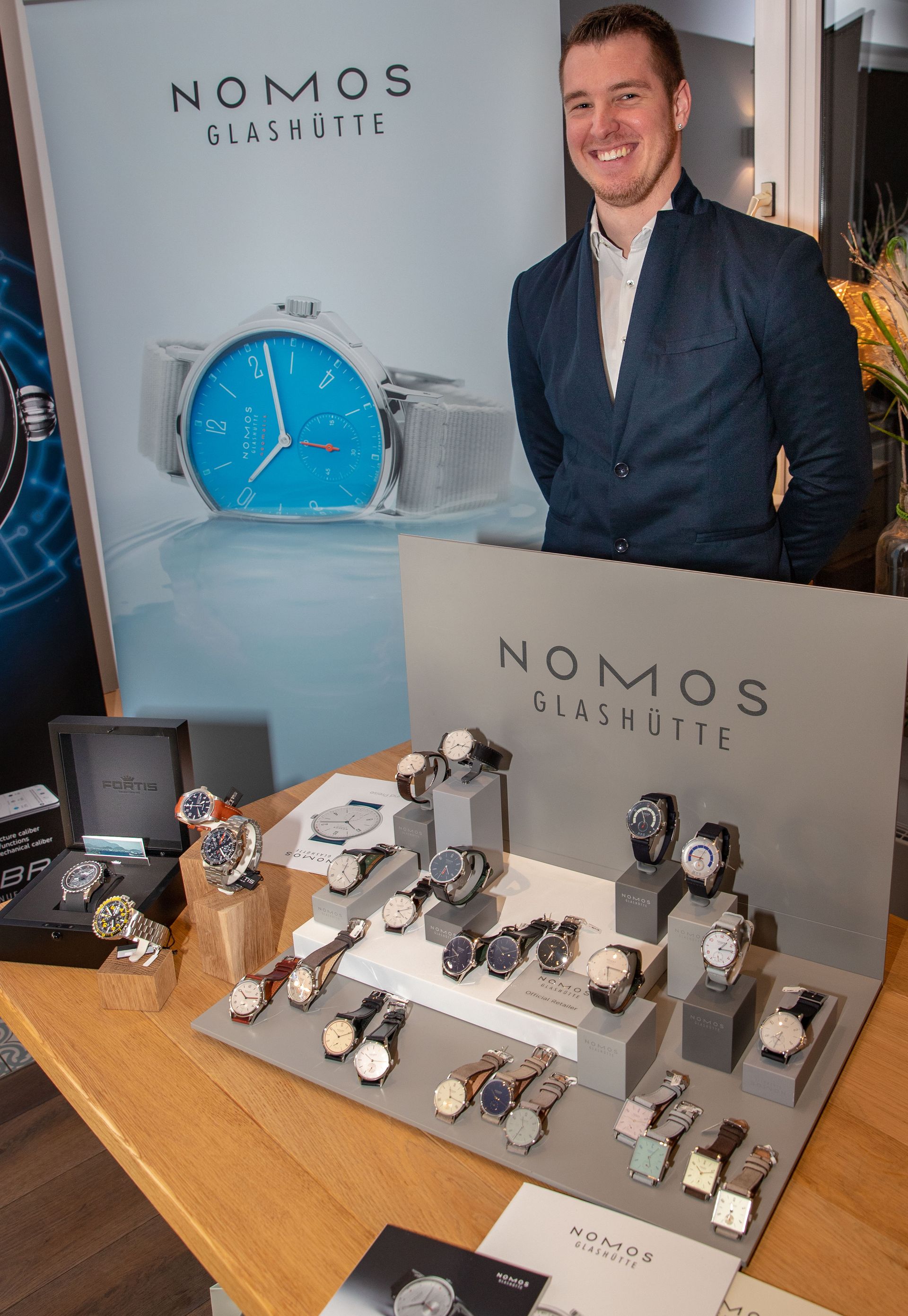 Ein Mann steht vor einem Nomos-Uhrendisplay