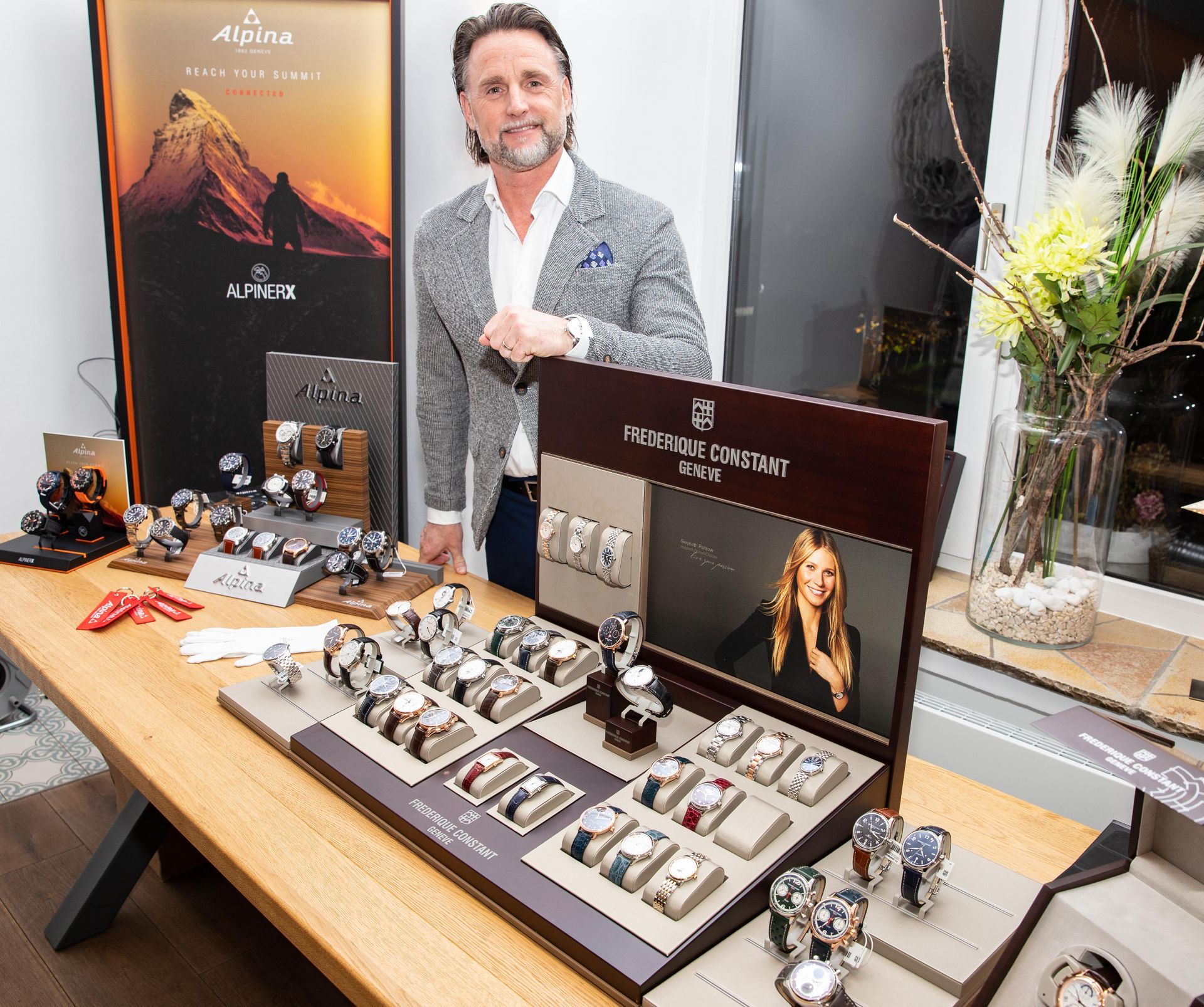 Ein Mann steht vor einem Tisch voller Uhren und einem Schild mit der Aufschrift „Anick“