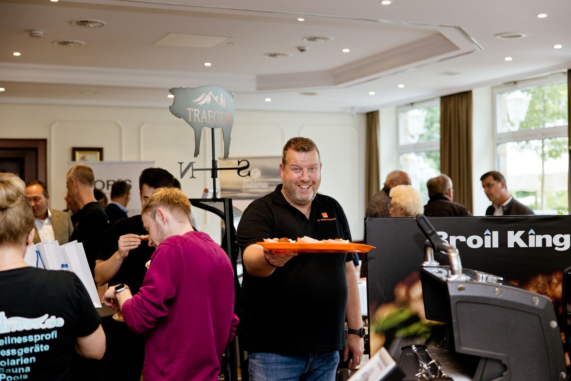 Ein Mann hält ein orangefarbenes Tablett vor einem Broll King-Schild