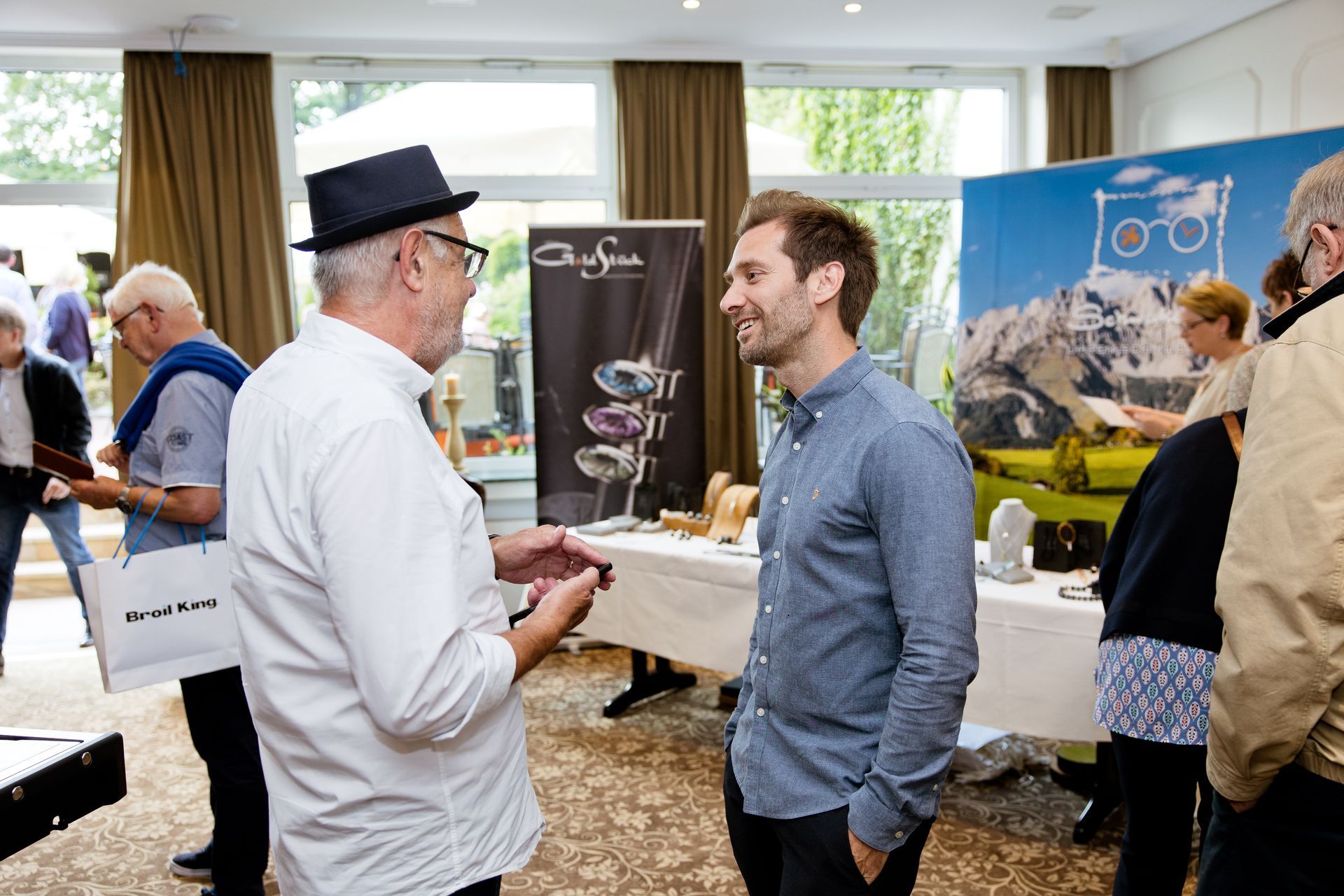 Ein Mann mit Hut spricht mit einem anderen Mann in einem Raum