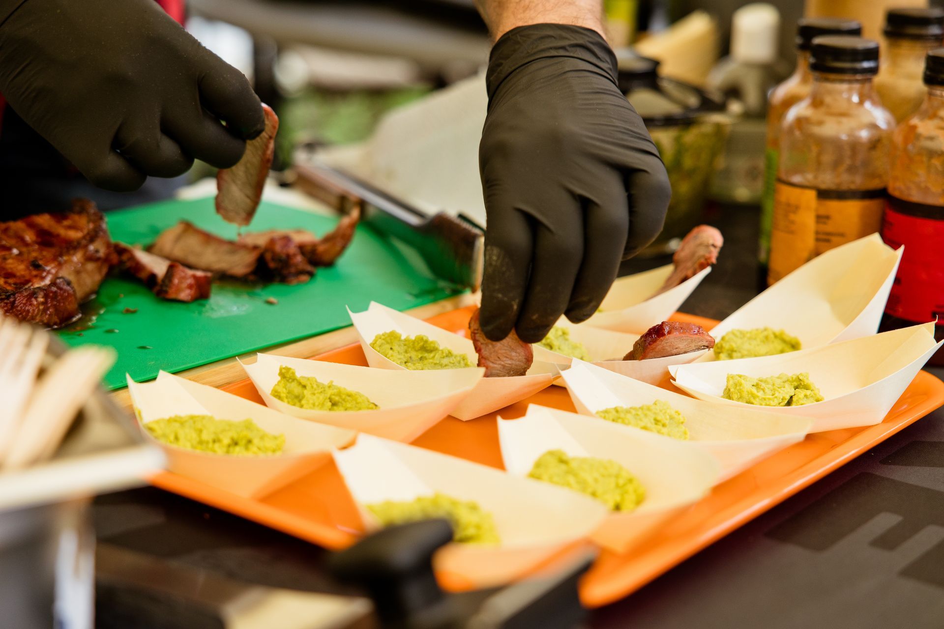 Eine Person mit schwarzen Handschuhen bereitet Essen auf einem Tablett zu