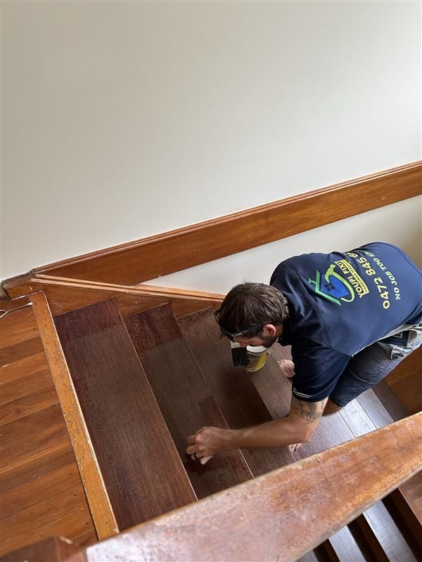 A Man Is Painting The Staris With A Paint Brush — Youfi Fixit Handyman Services in Edmonton, QLD