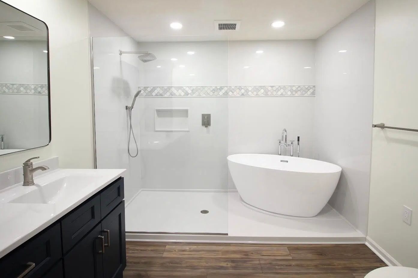 Modern bathroom with a white tub, walk-in shower, and dark vanity with a white countertop.