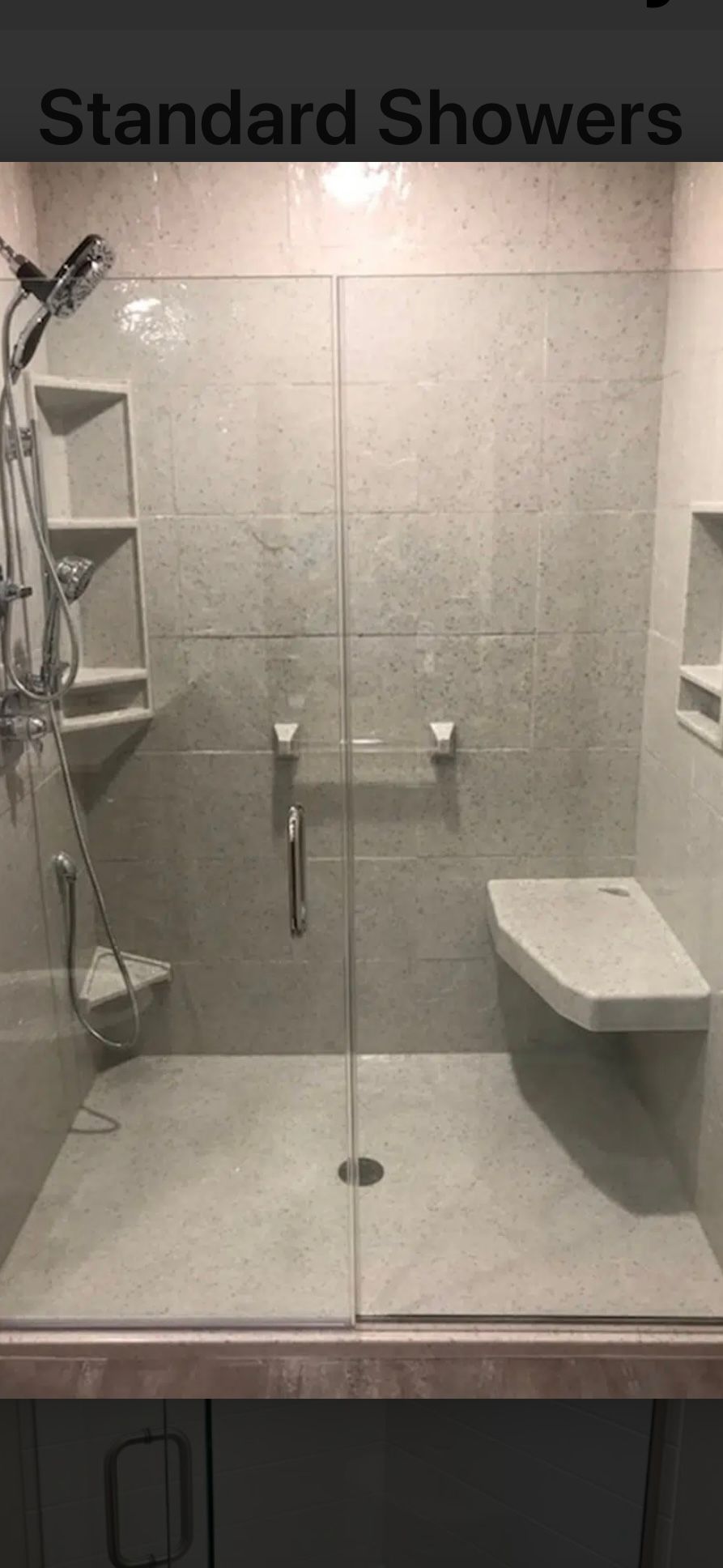 A modern, tiled shower with a glass door, built-in seat, and shelving.