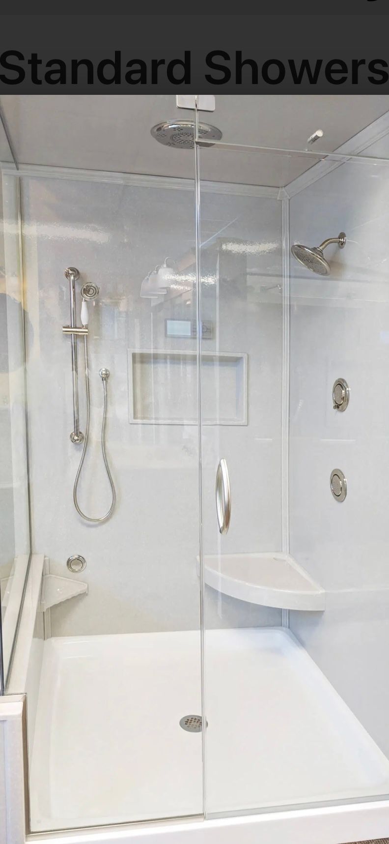 A modern, white shower with glass doors, a built-in seat, and multiple showerheads.