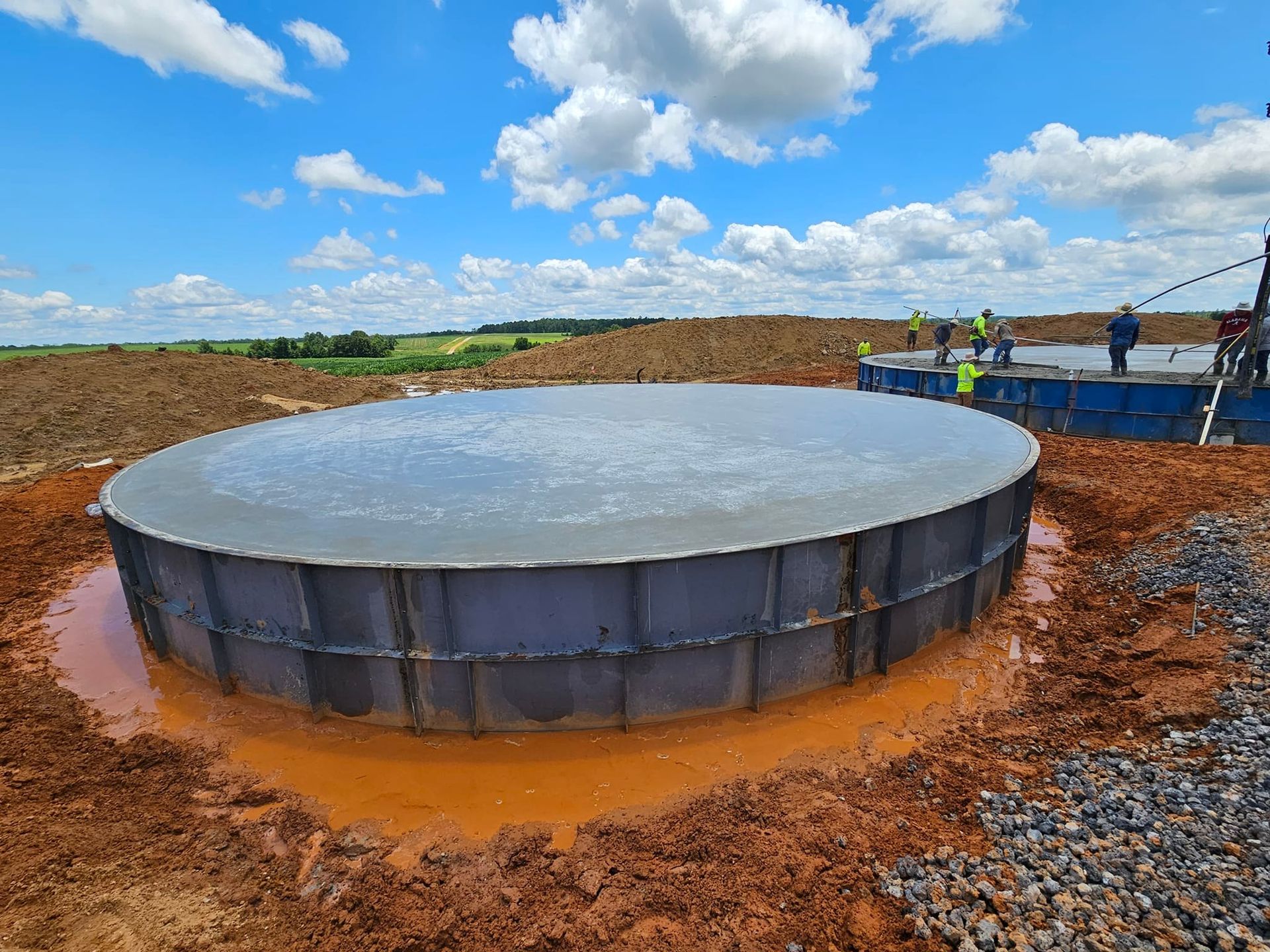 A large concrete cylinder is sitting in the middle of a dirt field.