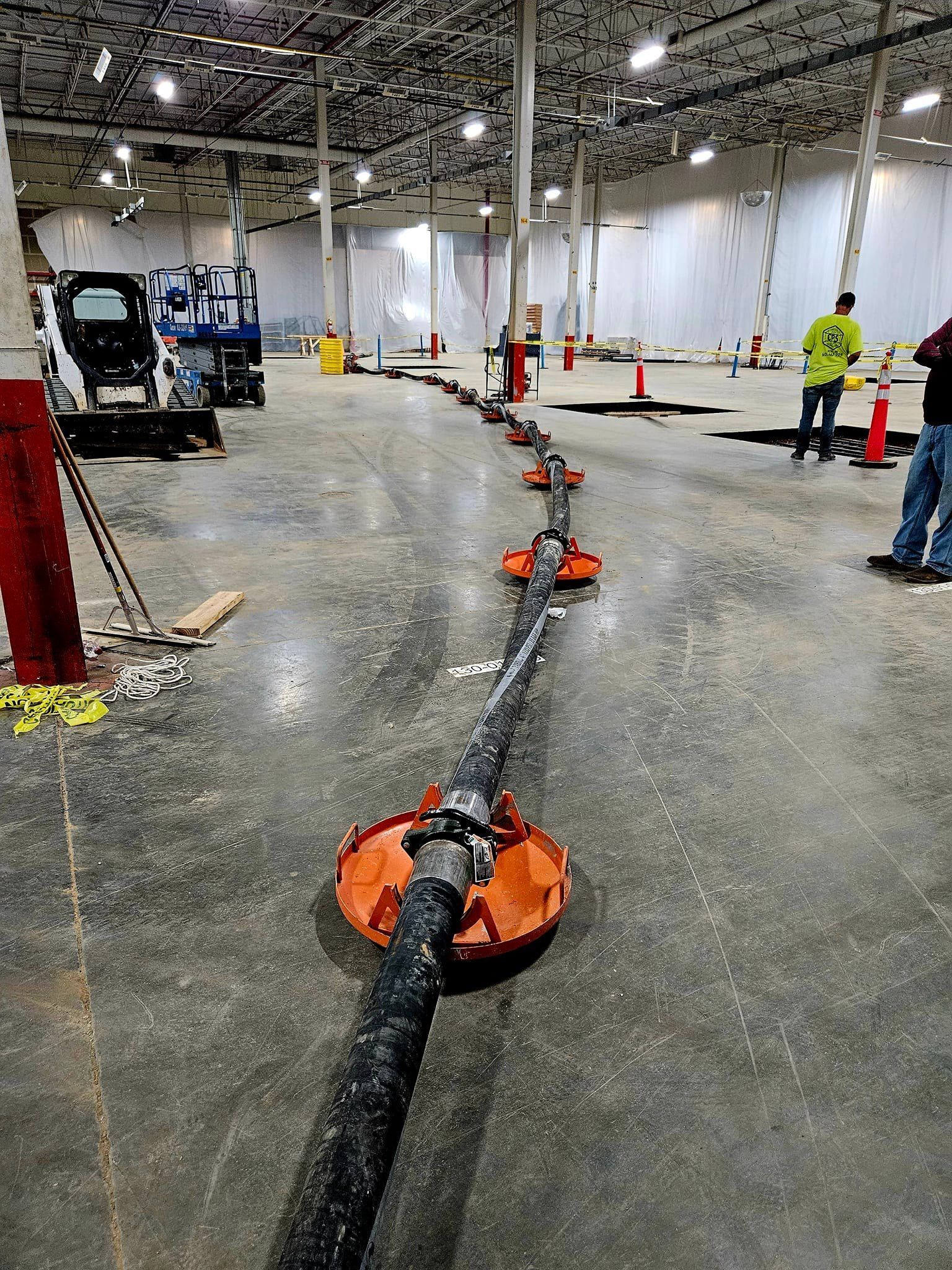 A large warehouse with a lot of pipes and cones on the floor.