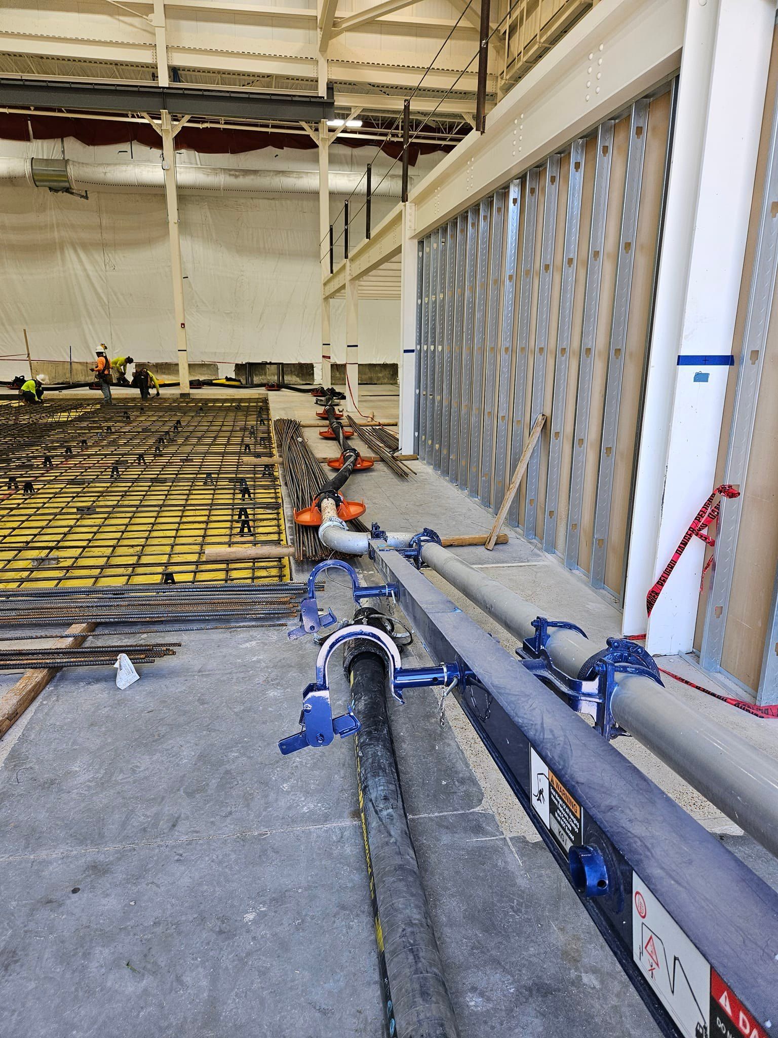 A large building under construction with pipes hanging from the ceiling.