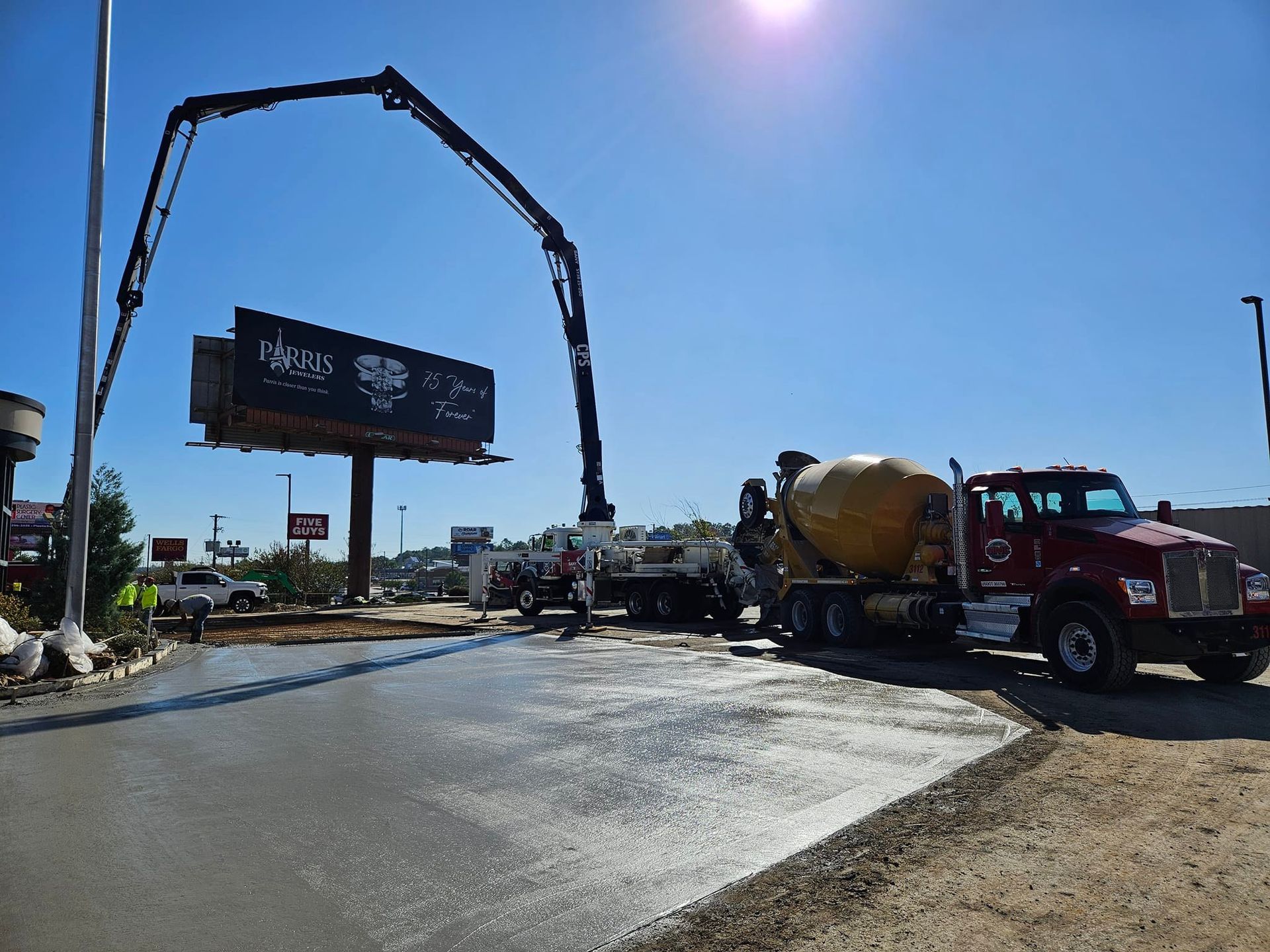 A concrete mixer truck is being used to pour concrete on a road.