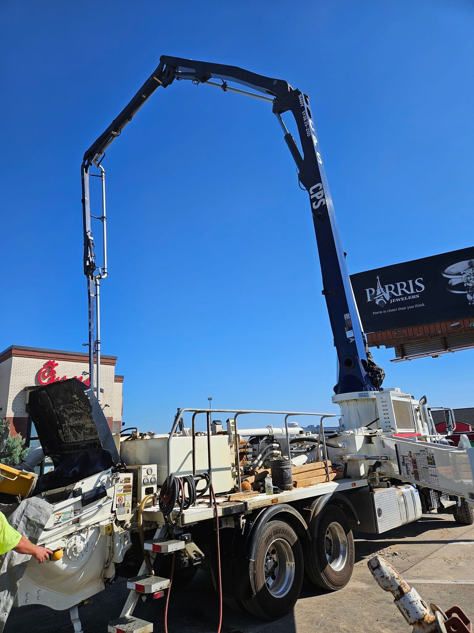 A man is standing next to a truck with a crane attached to it.