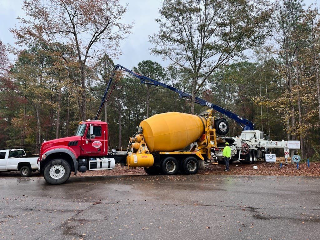A red and yellow concrete mixer truck is parked in a parking lot.