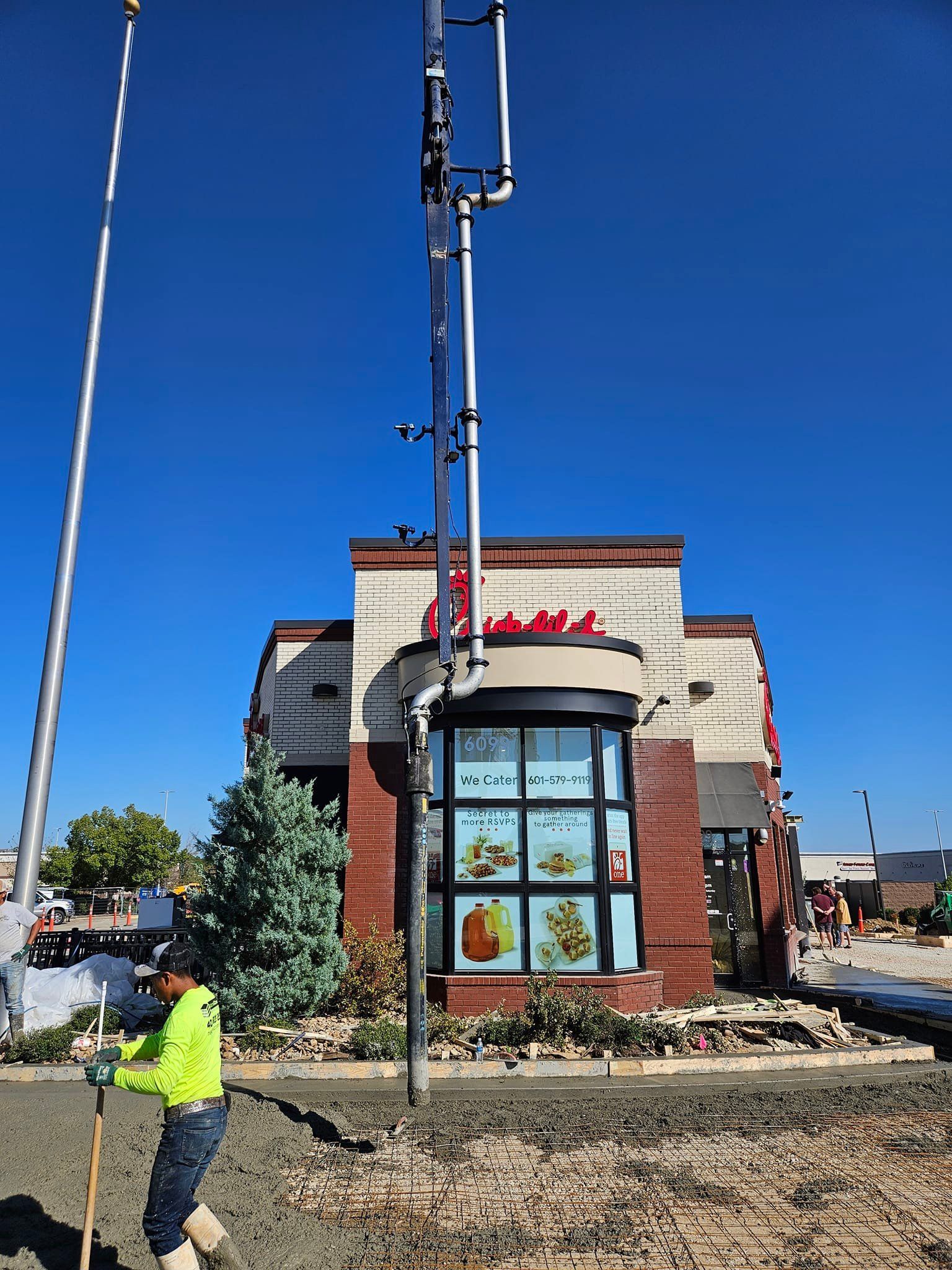 A man is standing in front of a chick fil a restaurant.