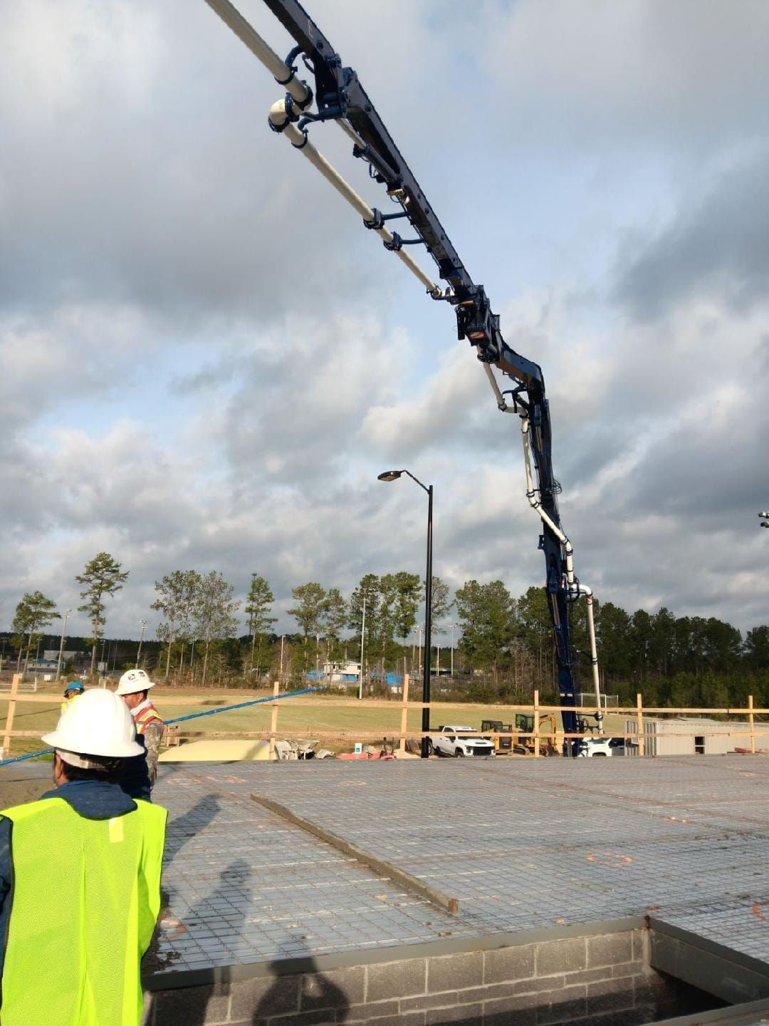 A man wearing a hard hat is standing in front of a concrete pump
