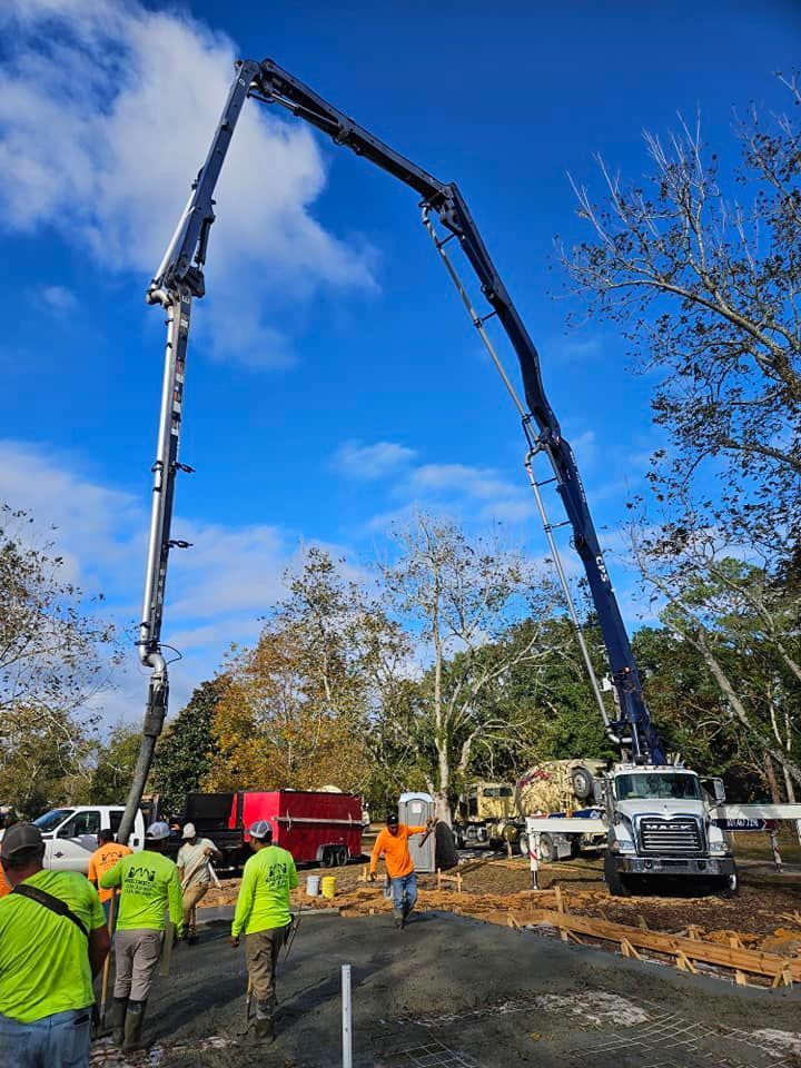 A group of construction workers are standing in front of a concrete pump truck.