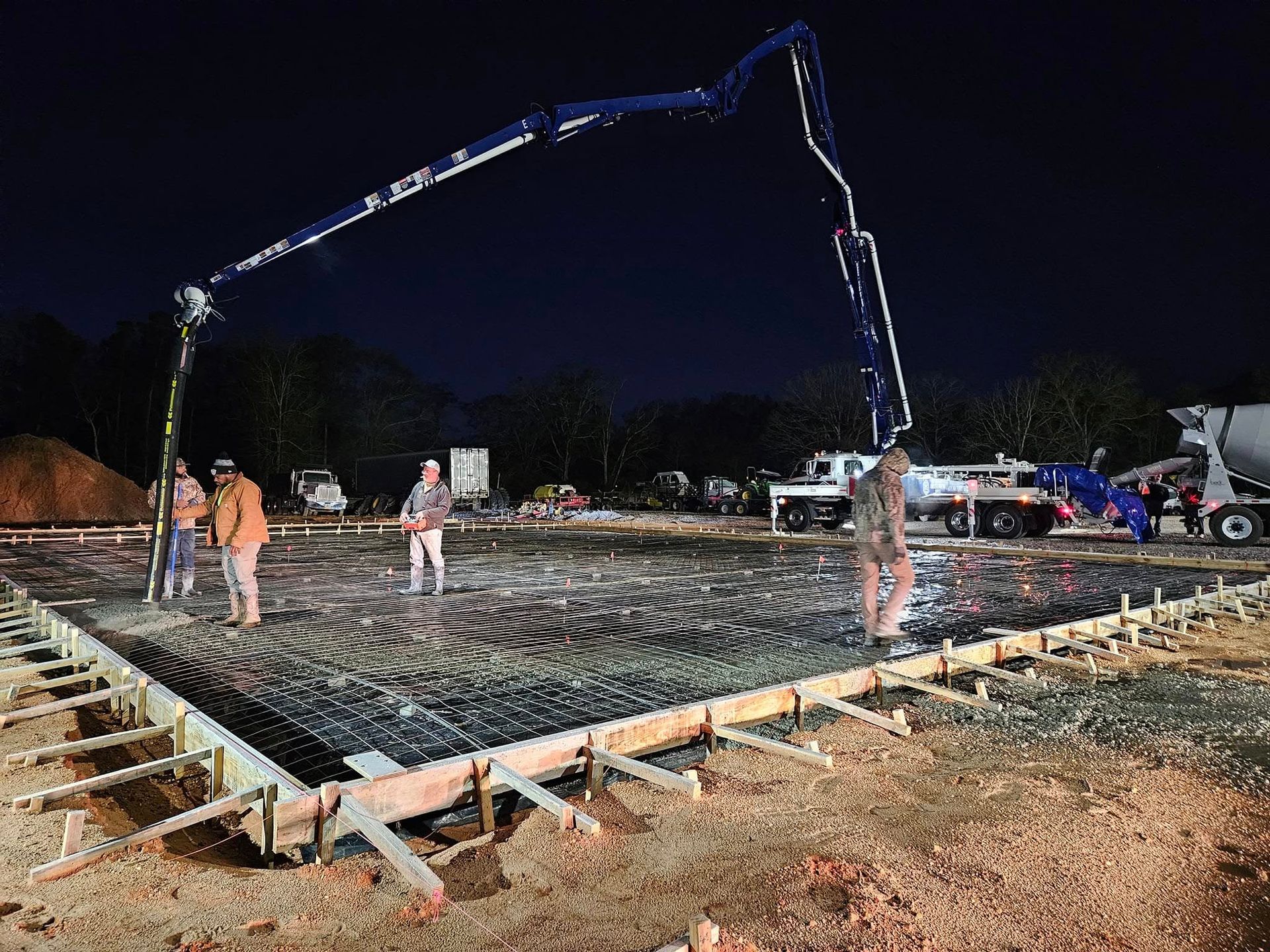 A concrete pump is being used to pour concrete on a construction site at night.