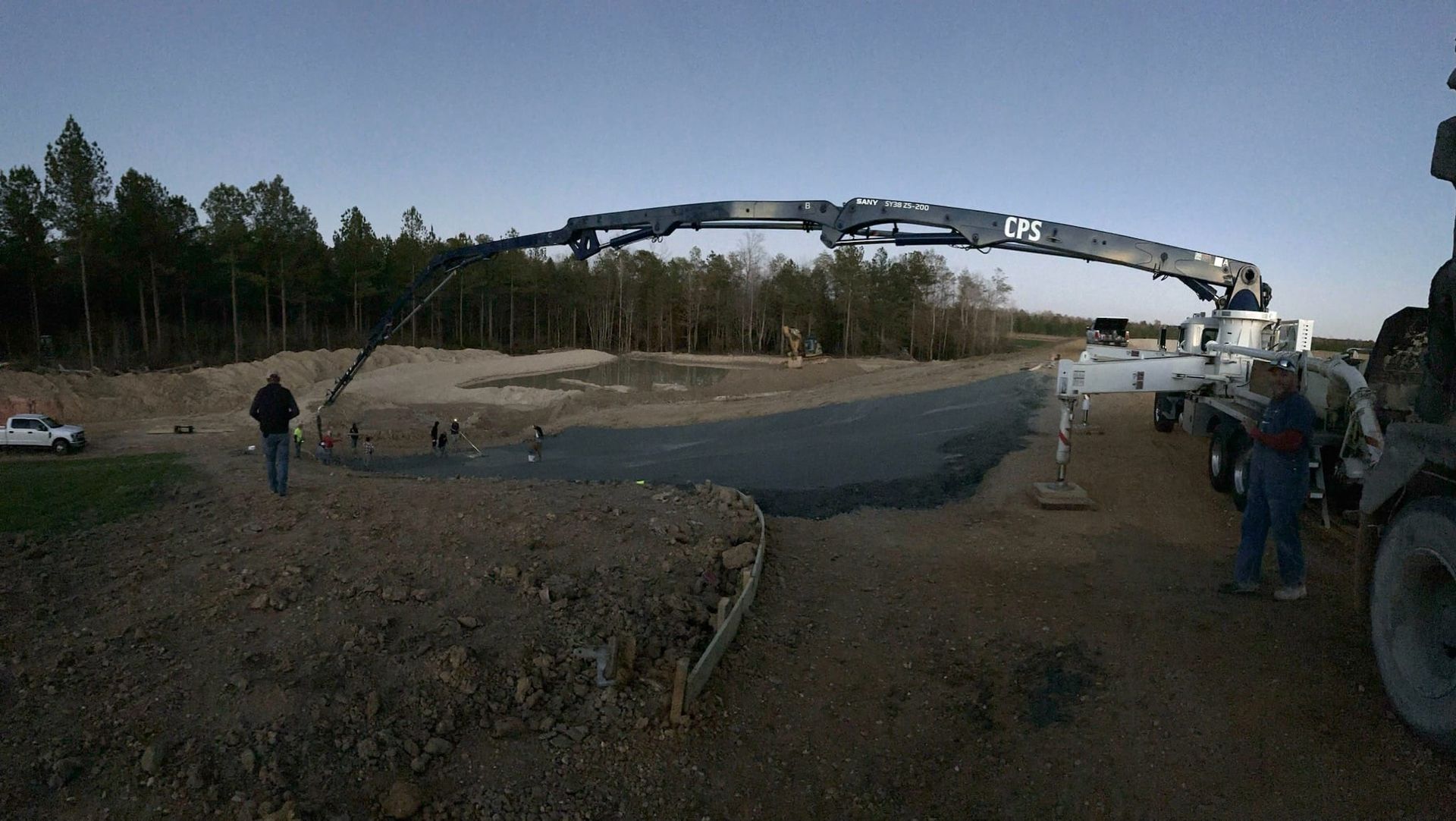 A large crane is being used to pump concrete into a pond