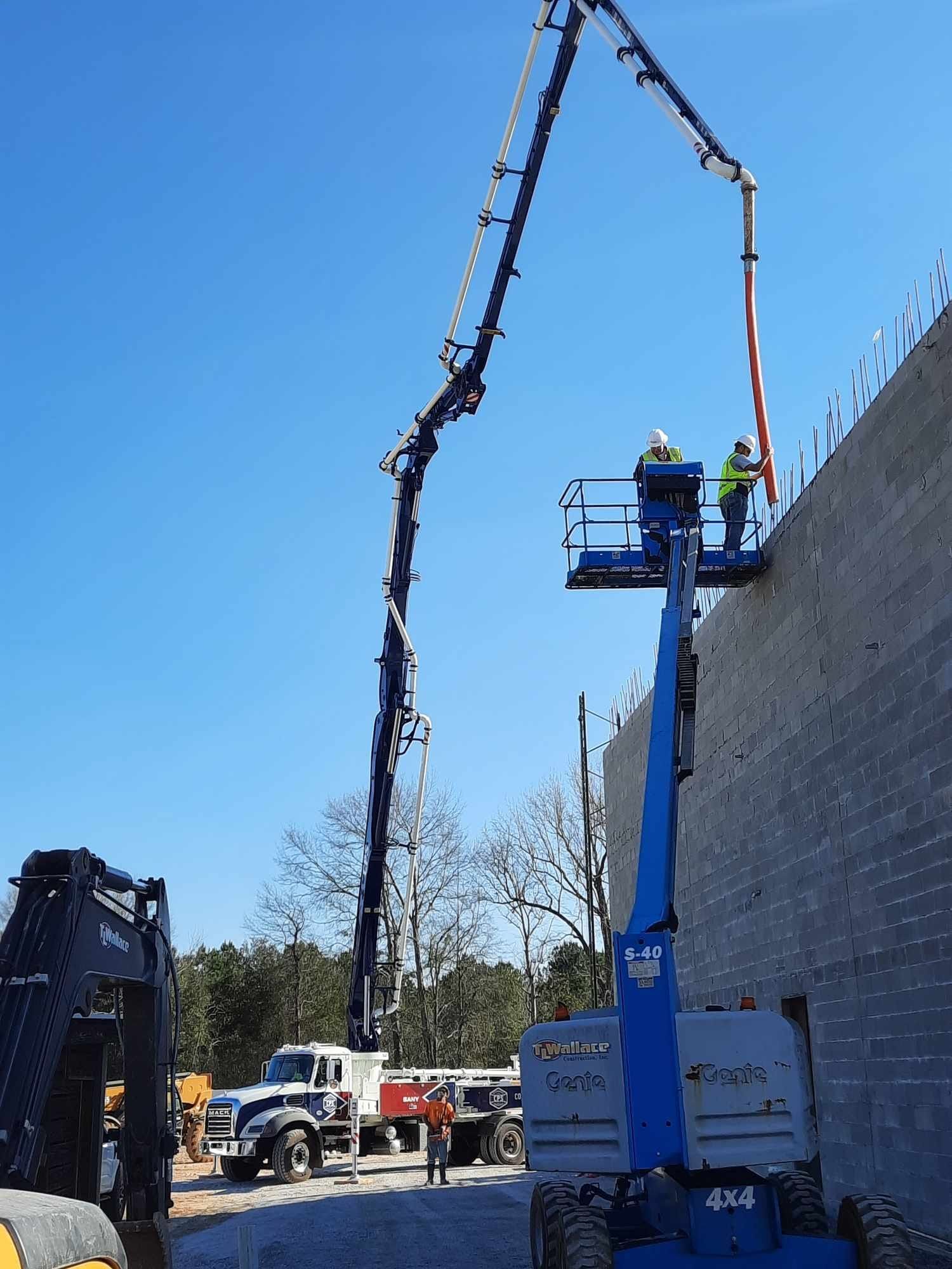 A concrete pump is being used to pour concrete into a wall.