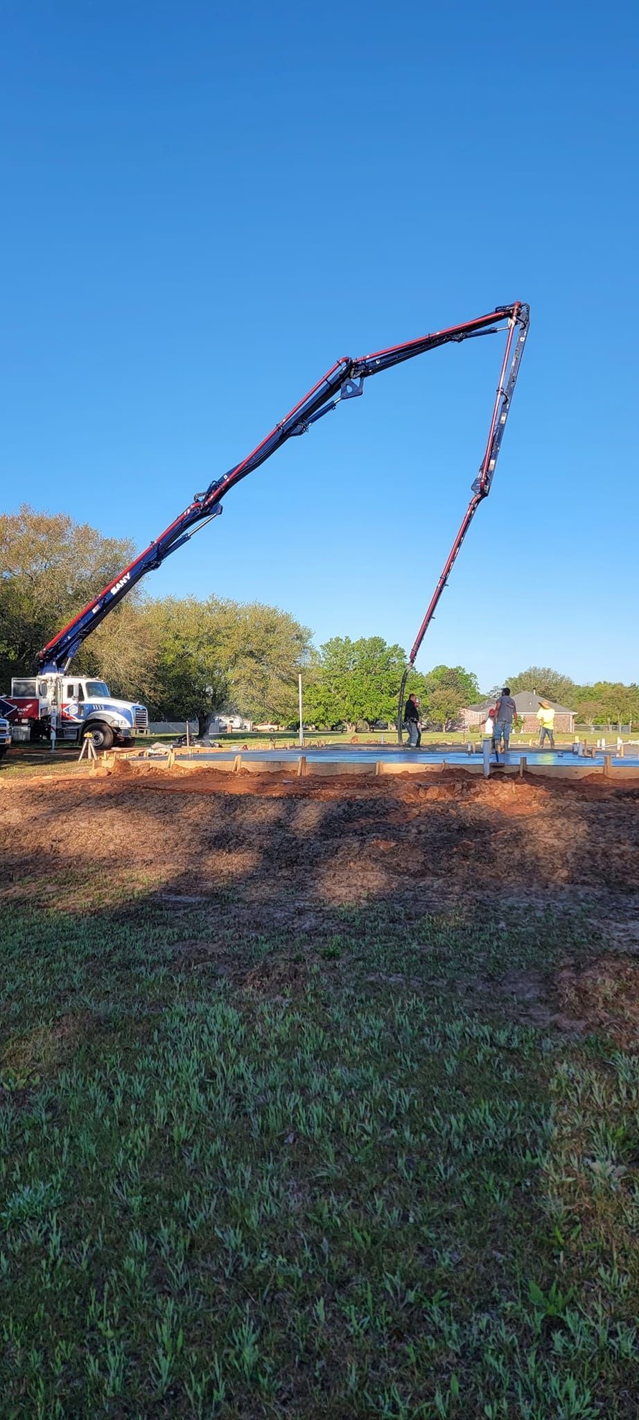 A concrete pump is being used to pour concrete into a field.