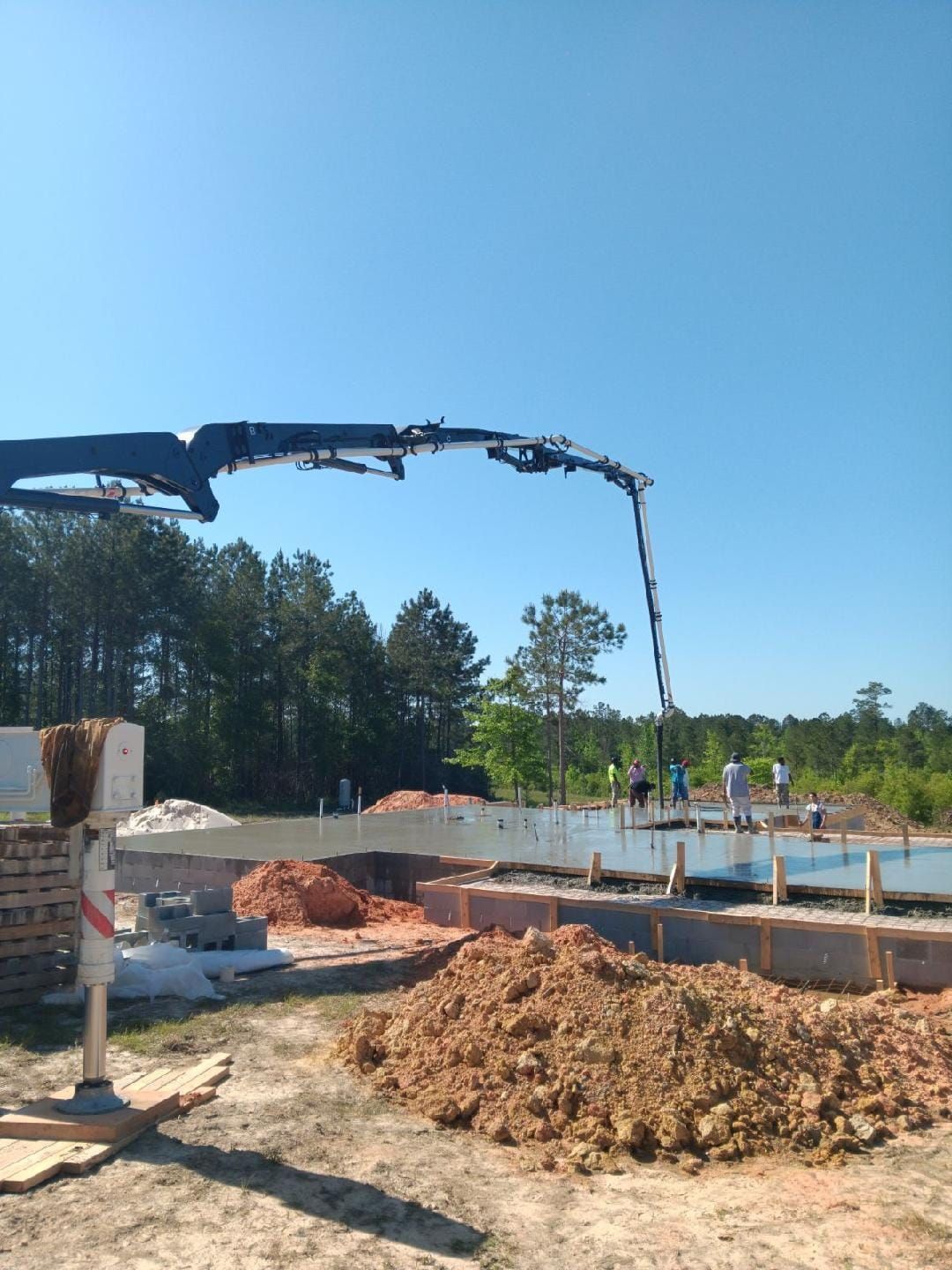 A crane is pouring concrete into a pile of dirt