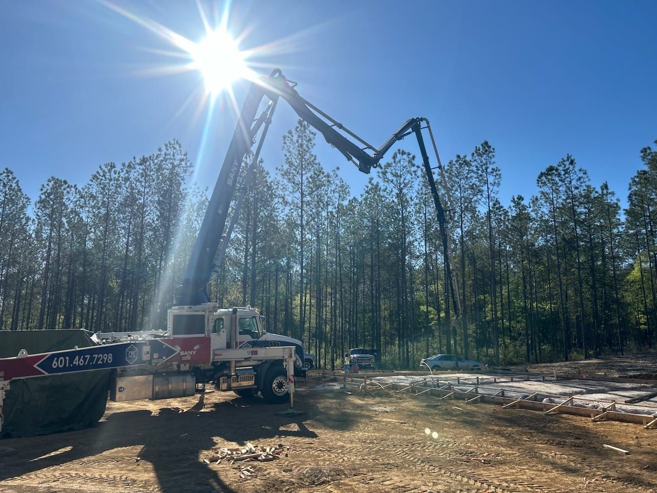A truck with a crane attached to it is driving down a dirt road.