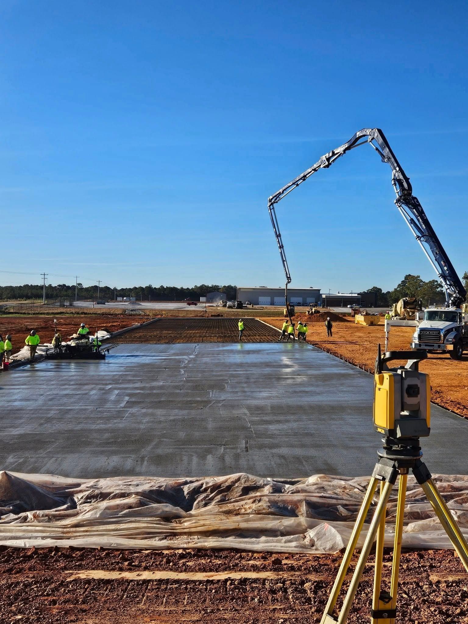 A construction site with a crane pouring concrete into the ground.