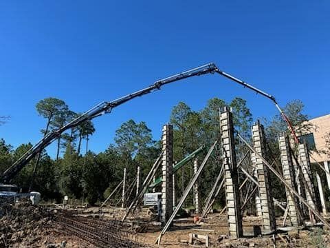 A crane is pouring concrete into a building under construction.