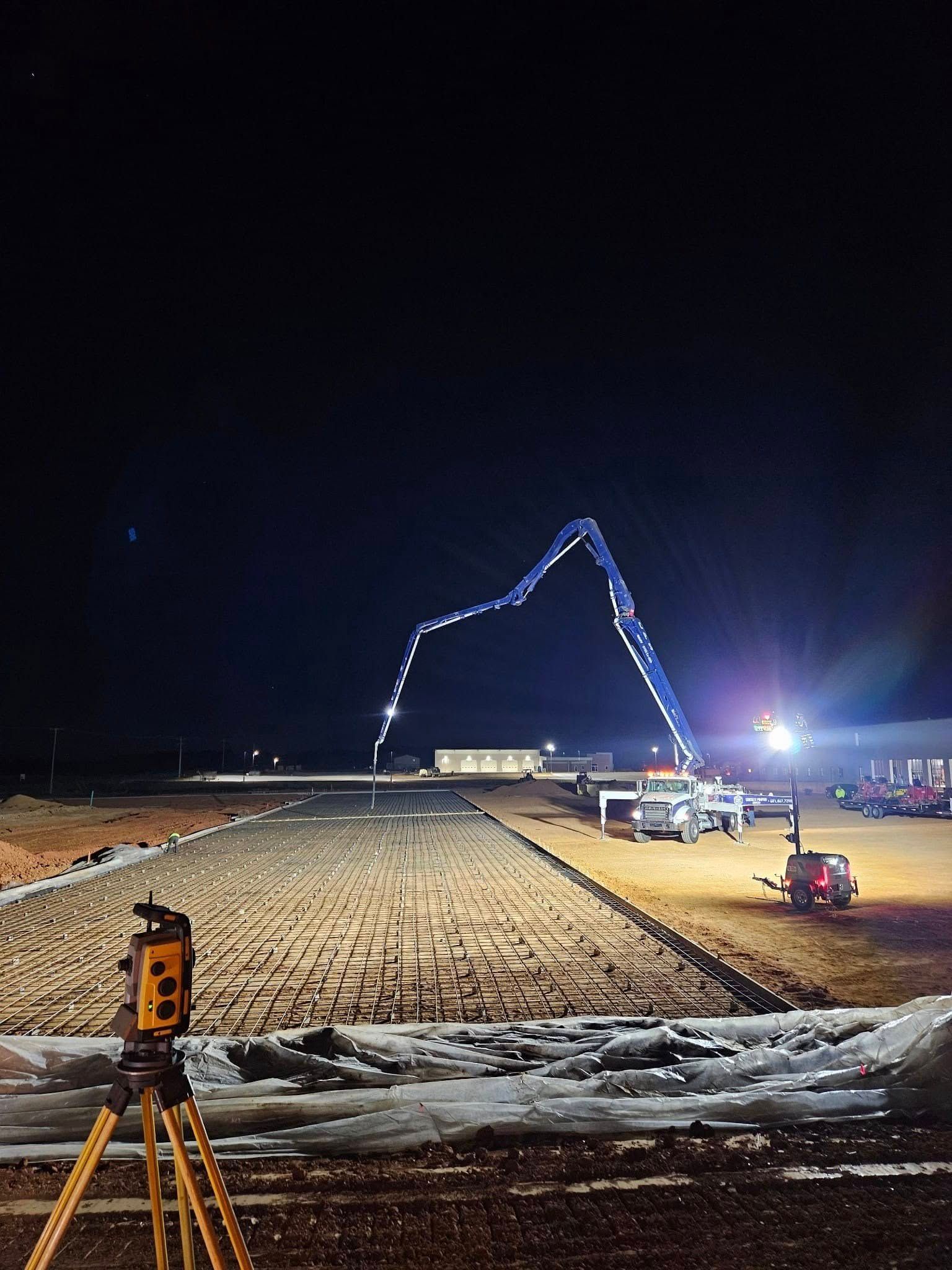 A construction site at night with a crane pumping concrete.